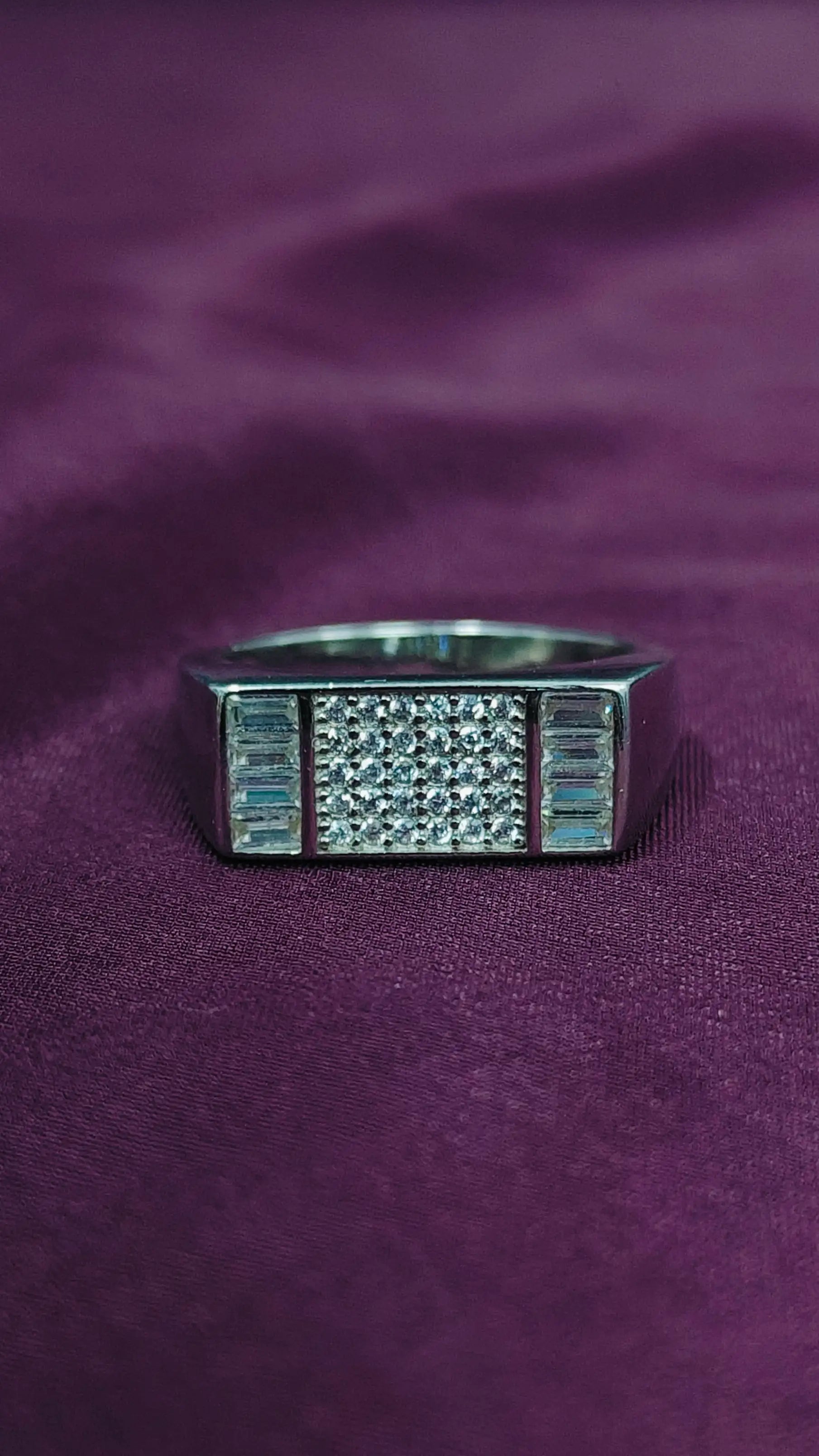 Silver ring with gemstones on a purple fabric background