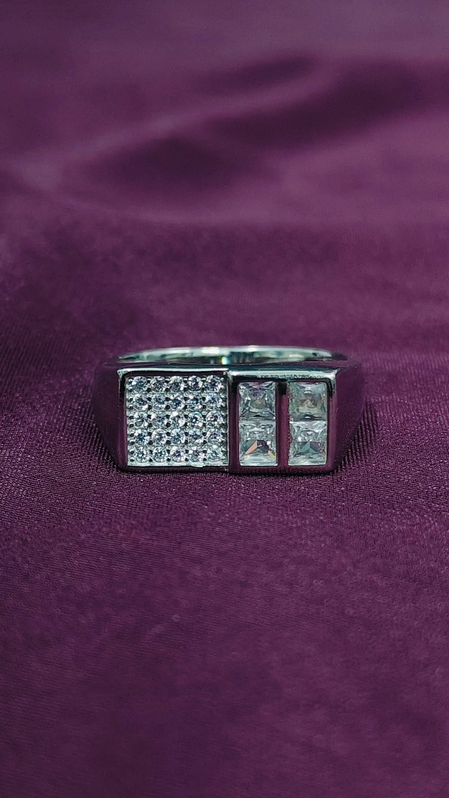 Silver ring with gemstones on a purple fabric background