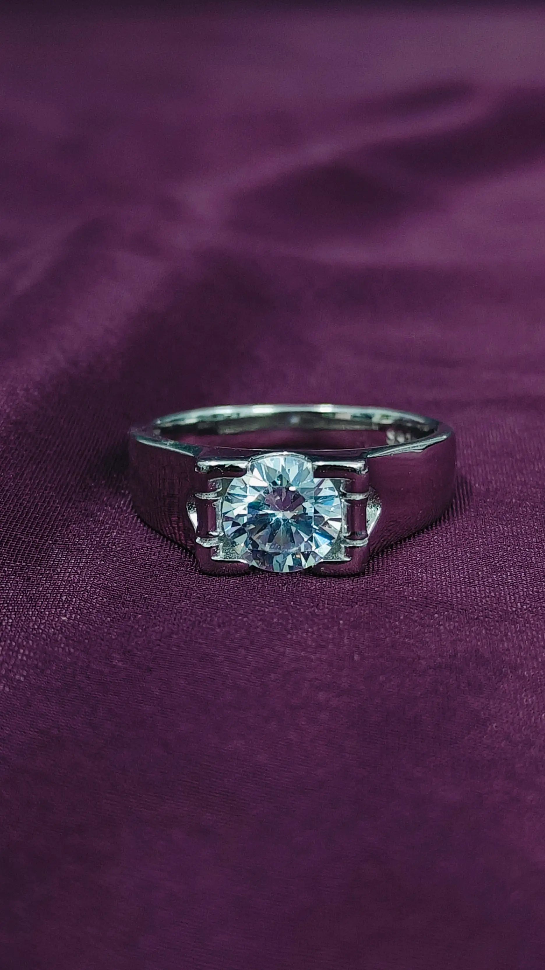 Silver ring with a large diamond on a purple fabric background