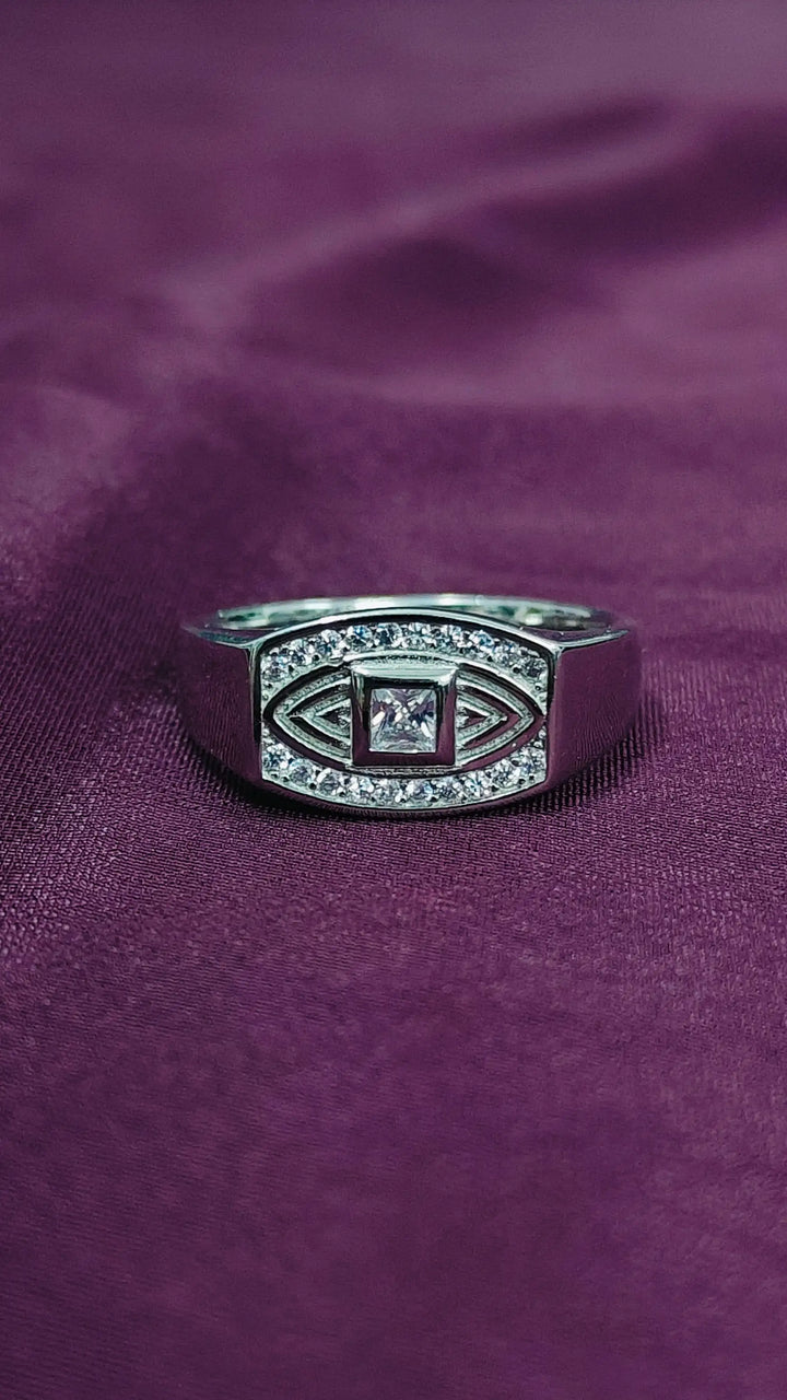 Silver ring with a central gemstone on a purple fabric background