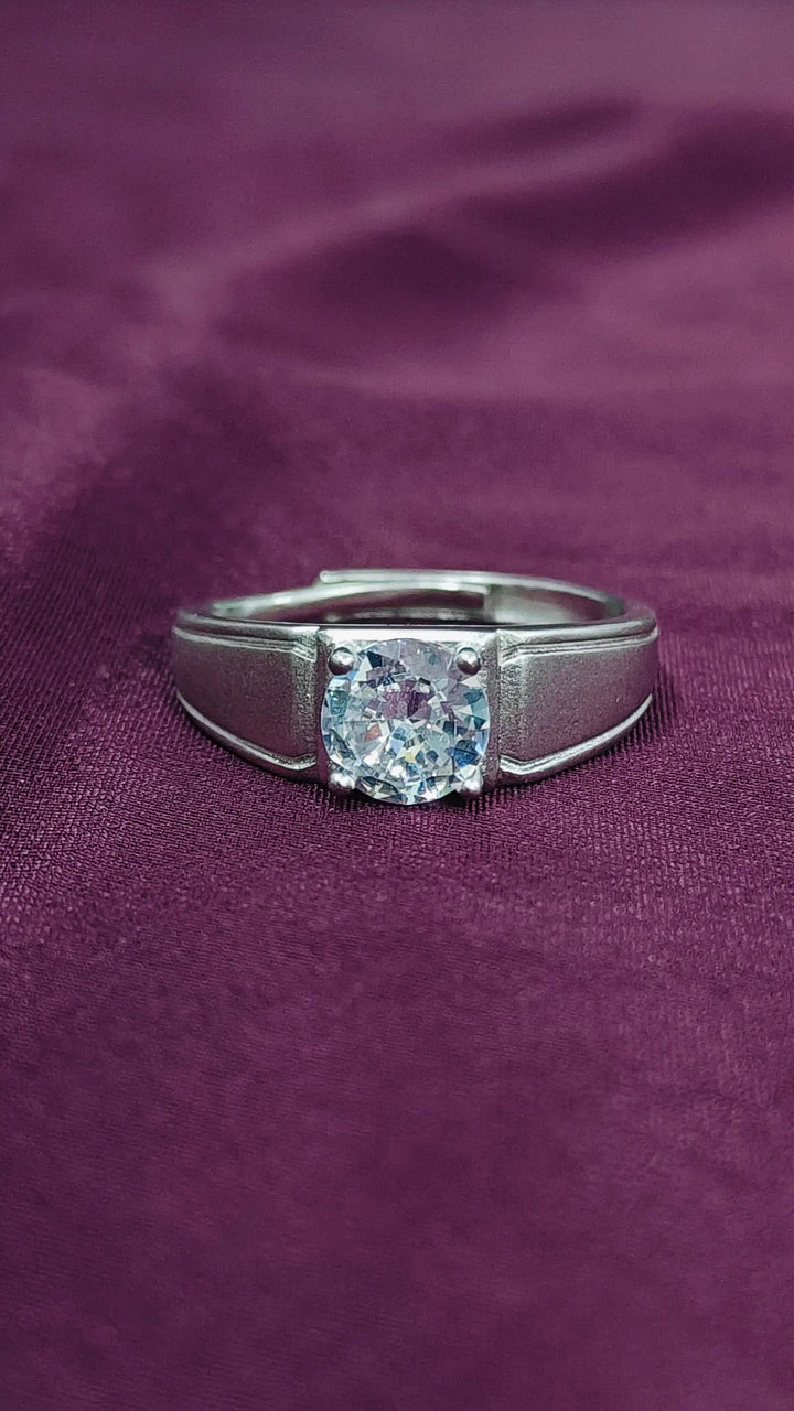 Silver ring with a large diamond on a purple fabric background
