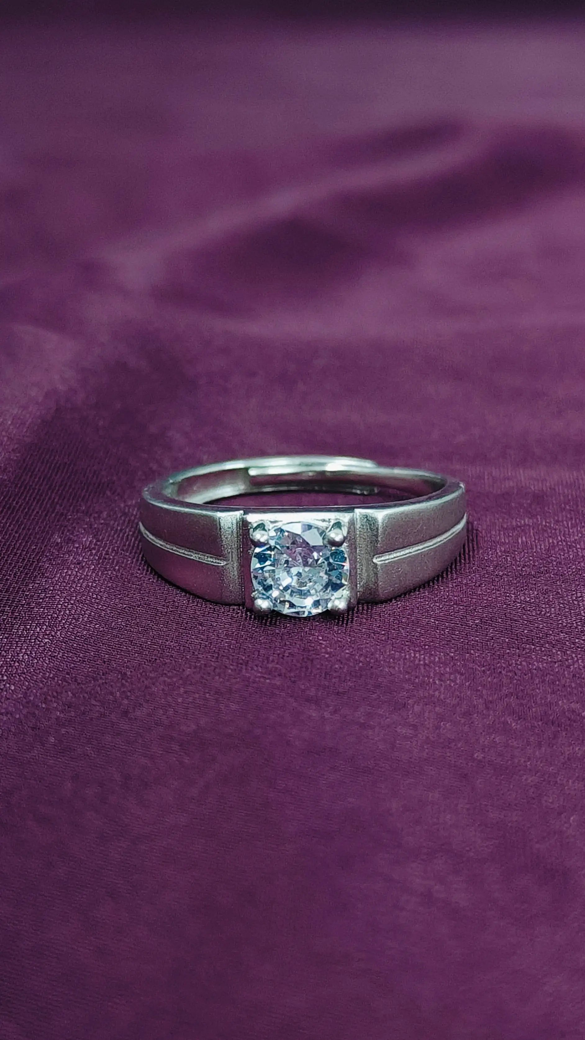 Silver ring with a diamond on a purple fabric background