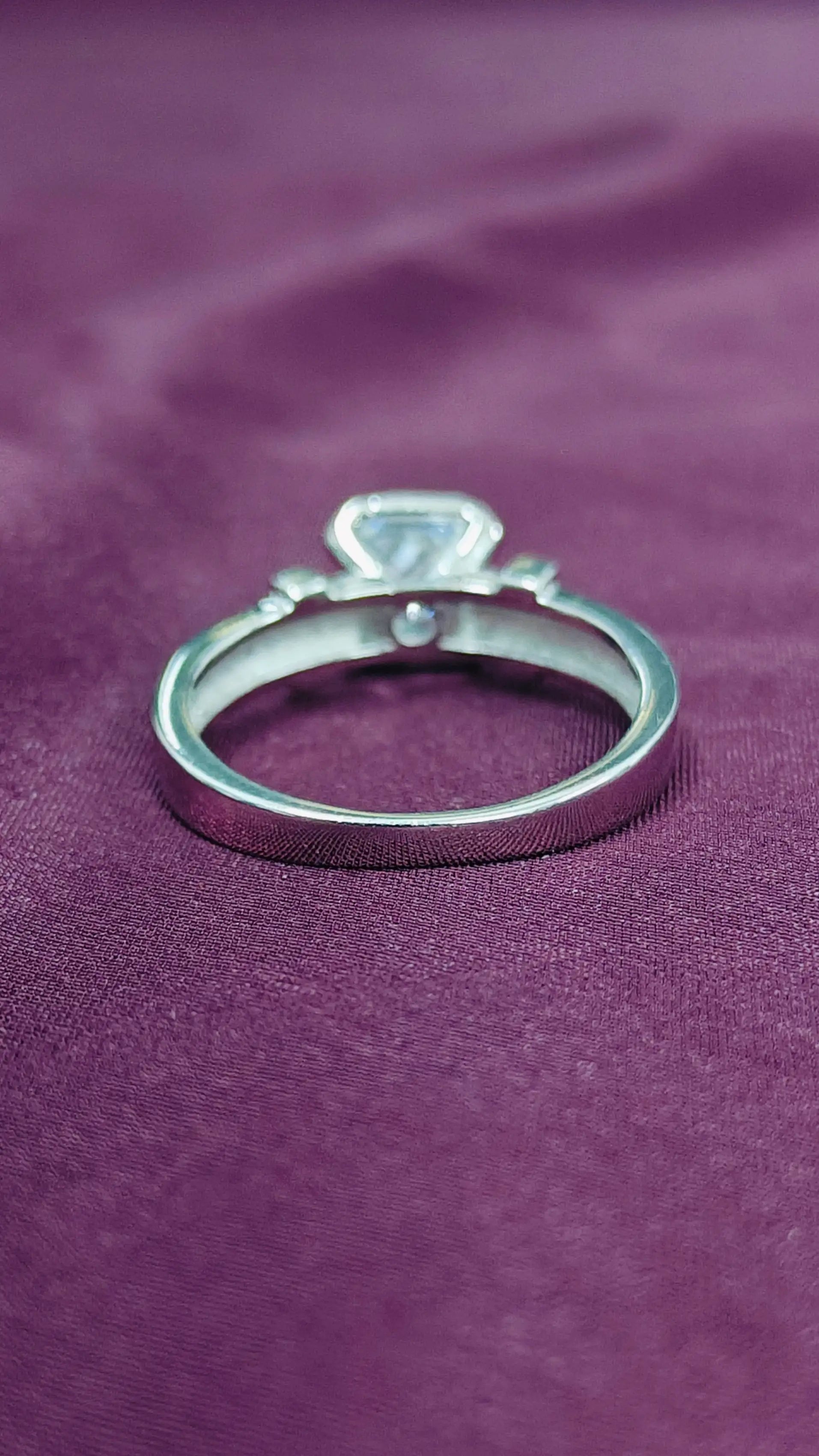 Silver ring with a diamond on a purple fabric background