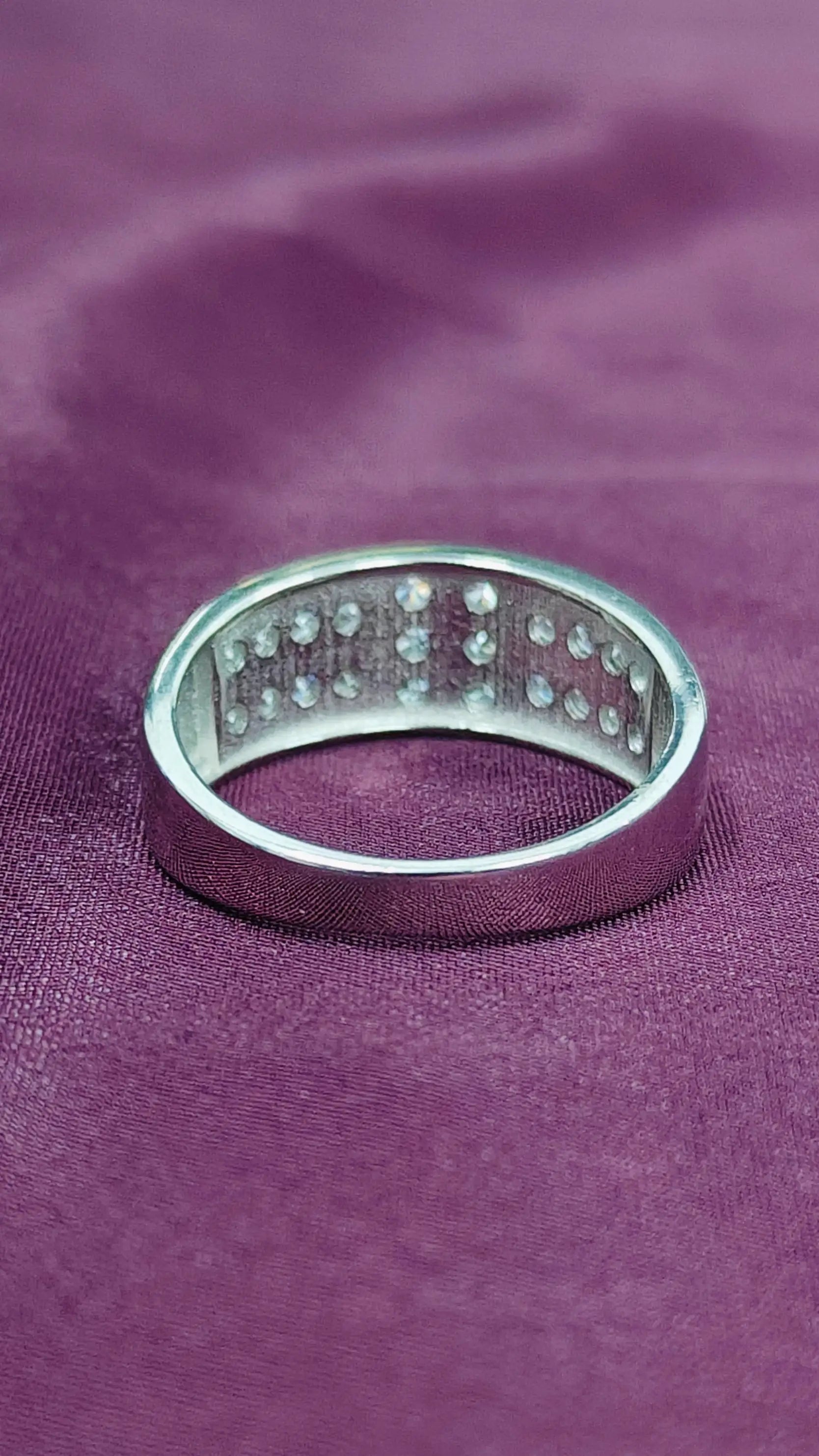 Silver ring with small stones on a purple fabric background