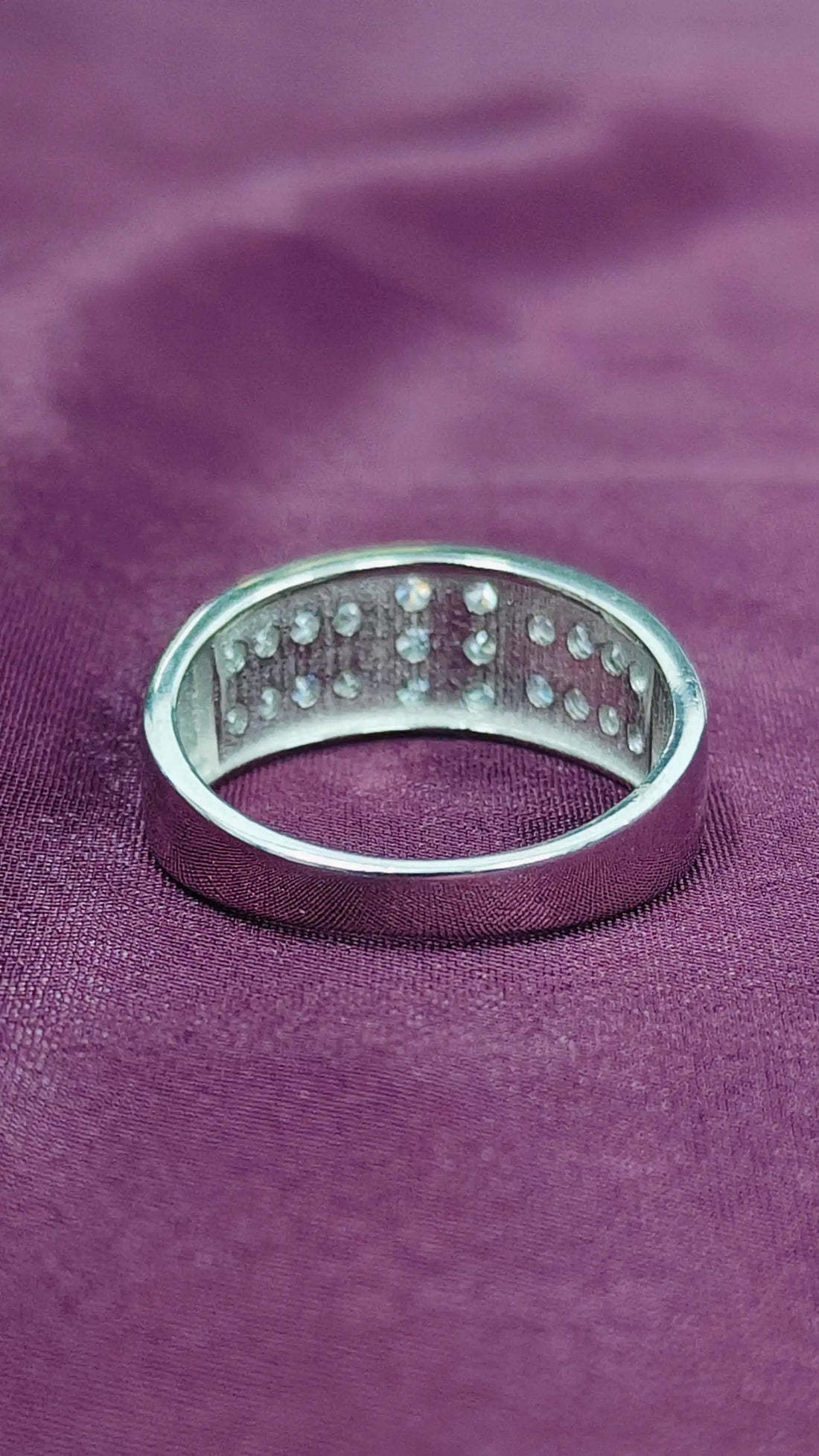Silver ring with small stones on a purple fabric background