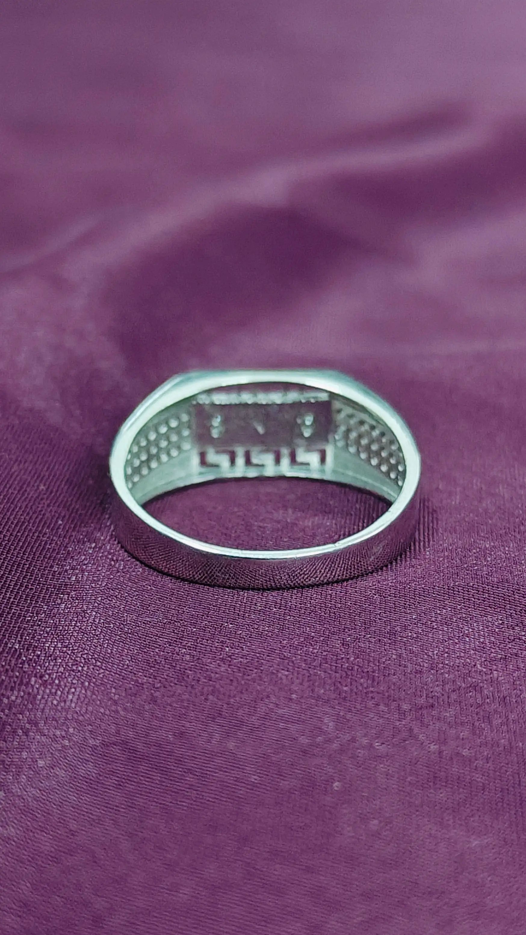 Silver ring on a purple fabric background