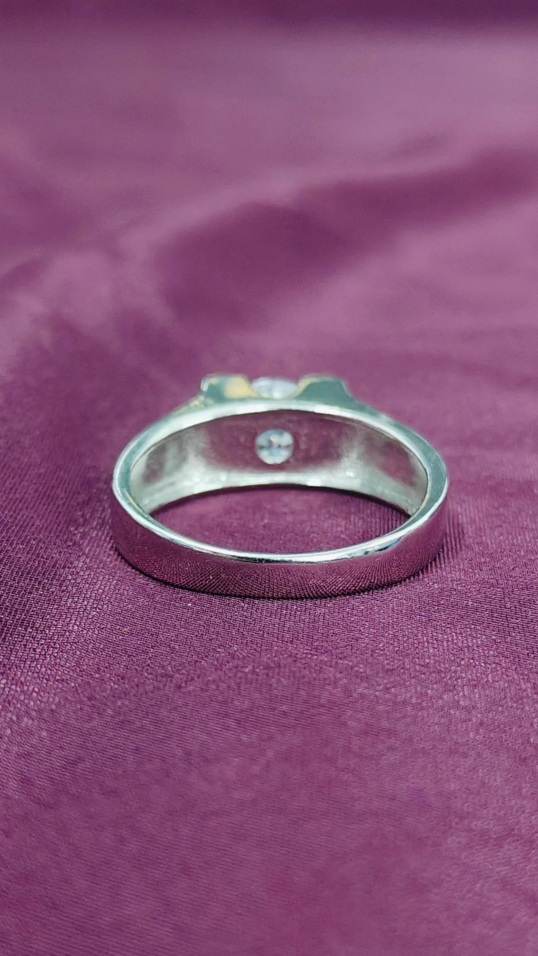 Silver ring with a small gemstone on a purple fabric background
