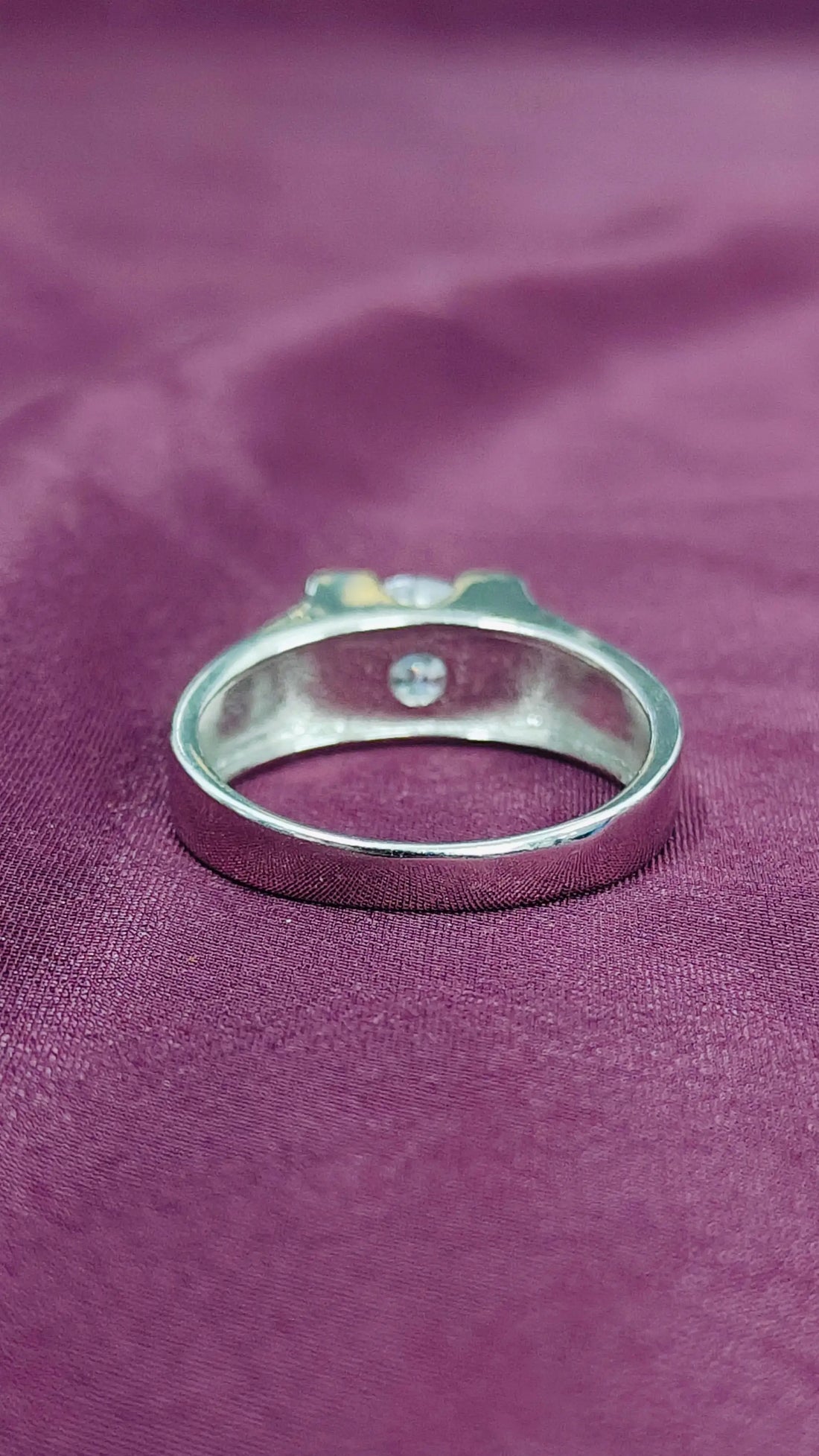 Silver ring with a small gemstone on a purple fabric background