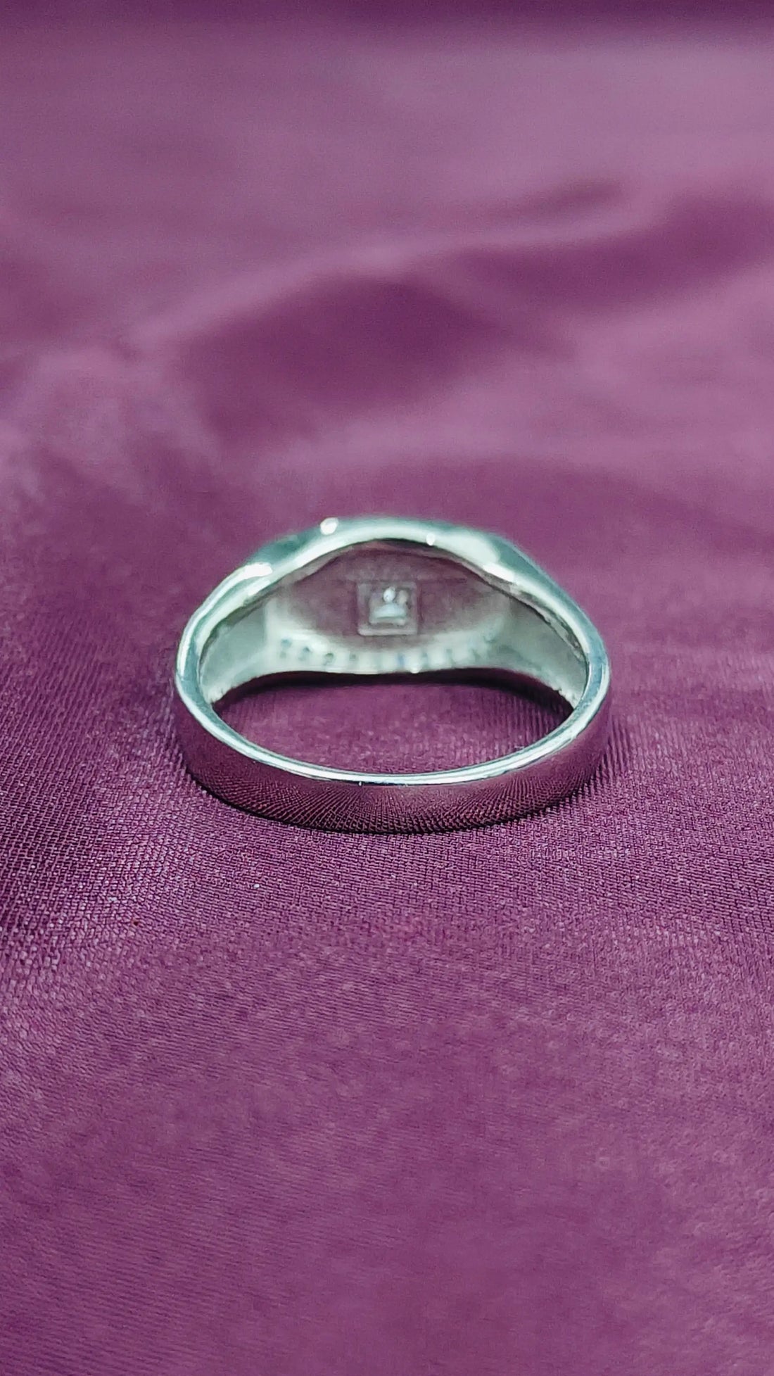 Silver ring with a diamond on a purple fabric background