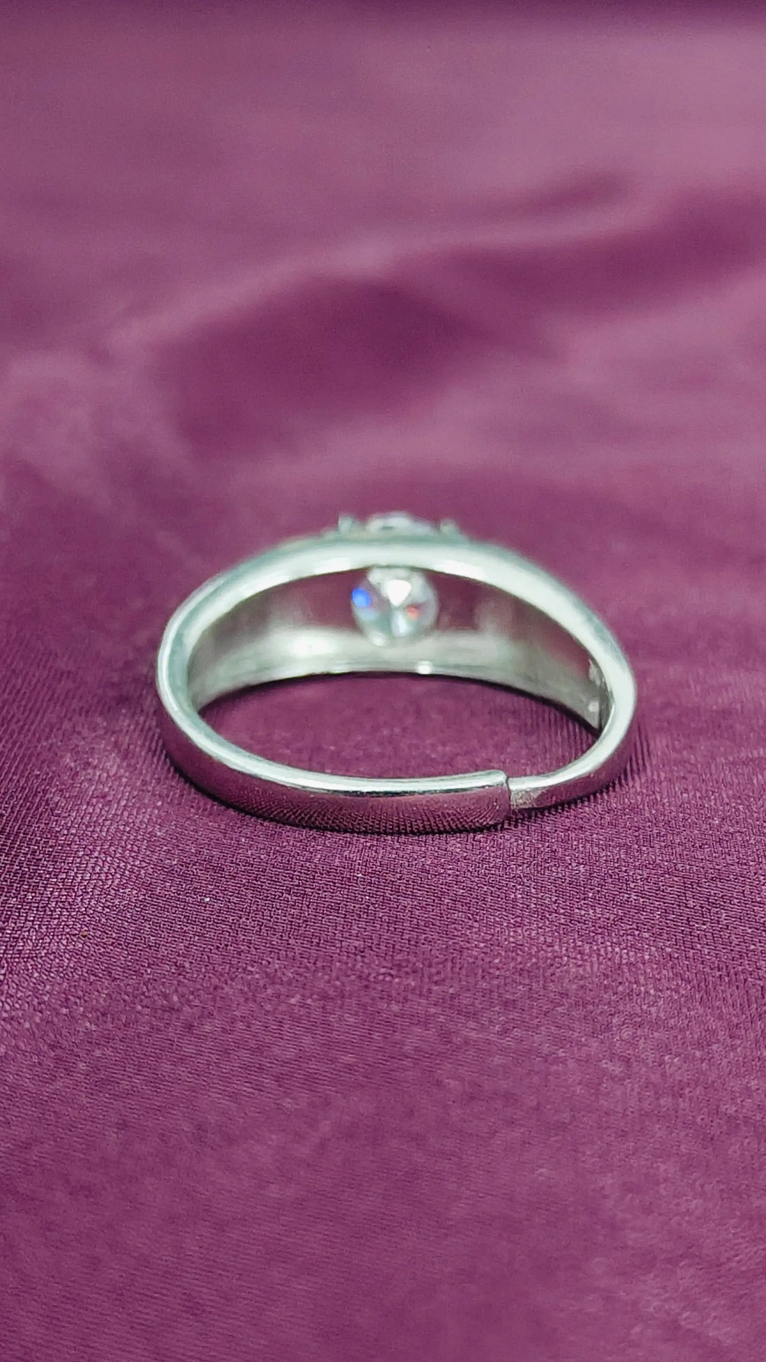 Silver ring with a gemstone on a purple fabric background