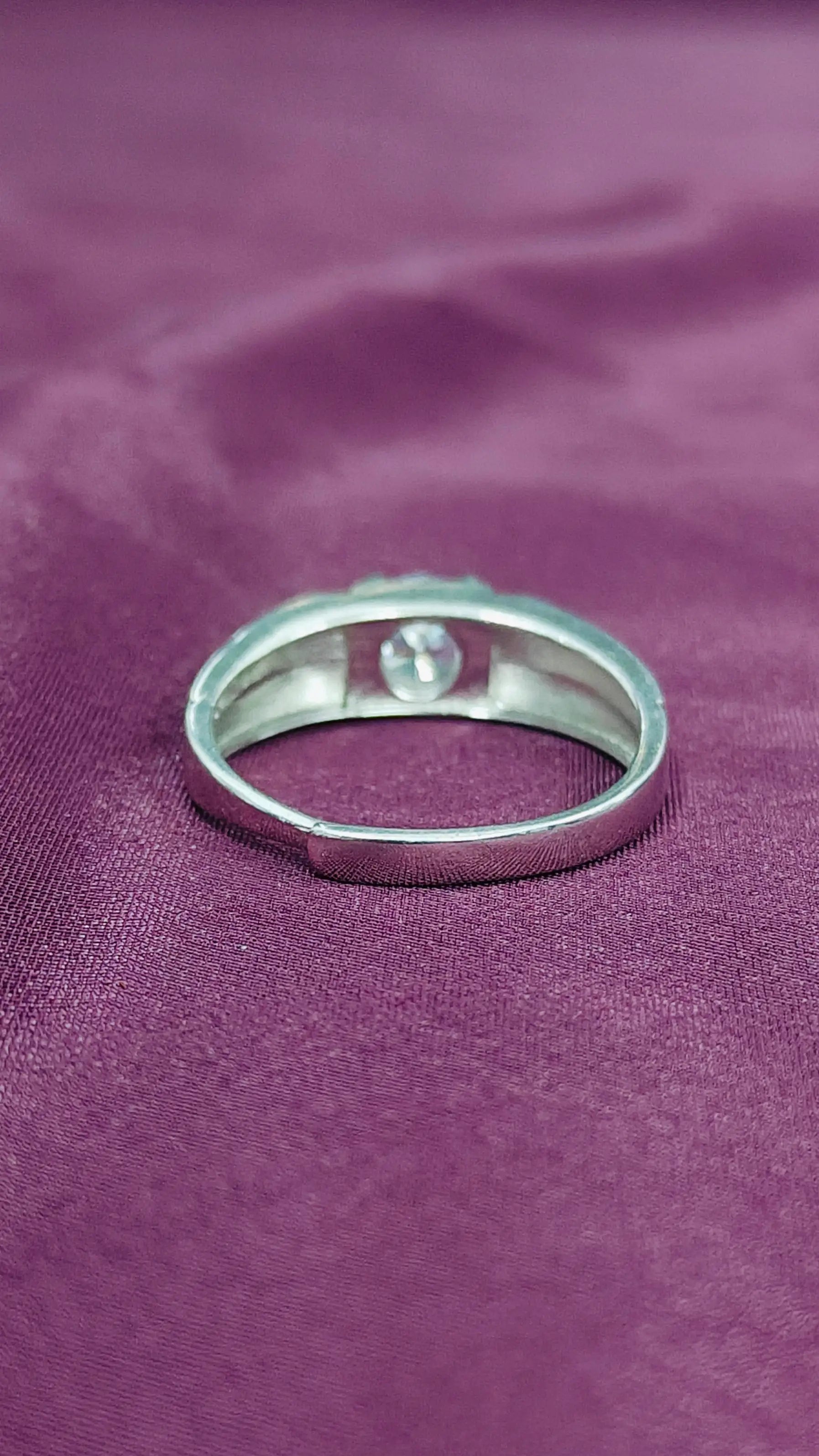 Silver ring with a small stone on a purple fabric background