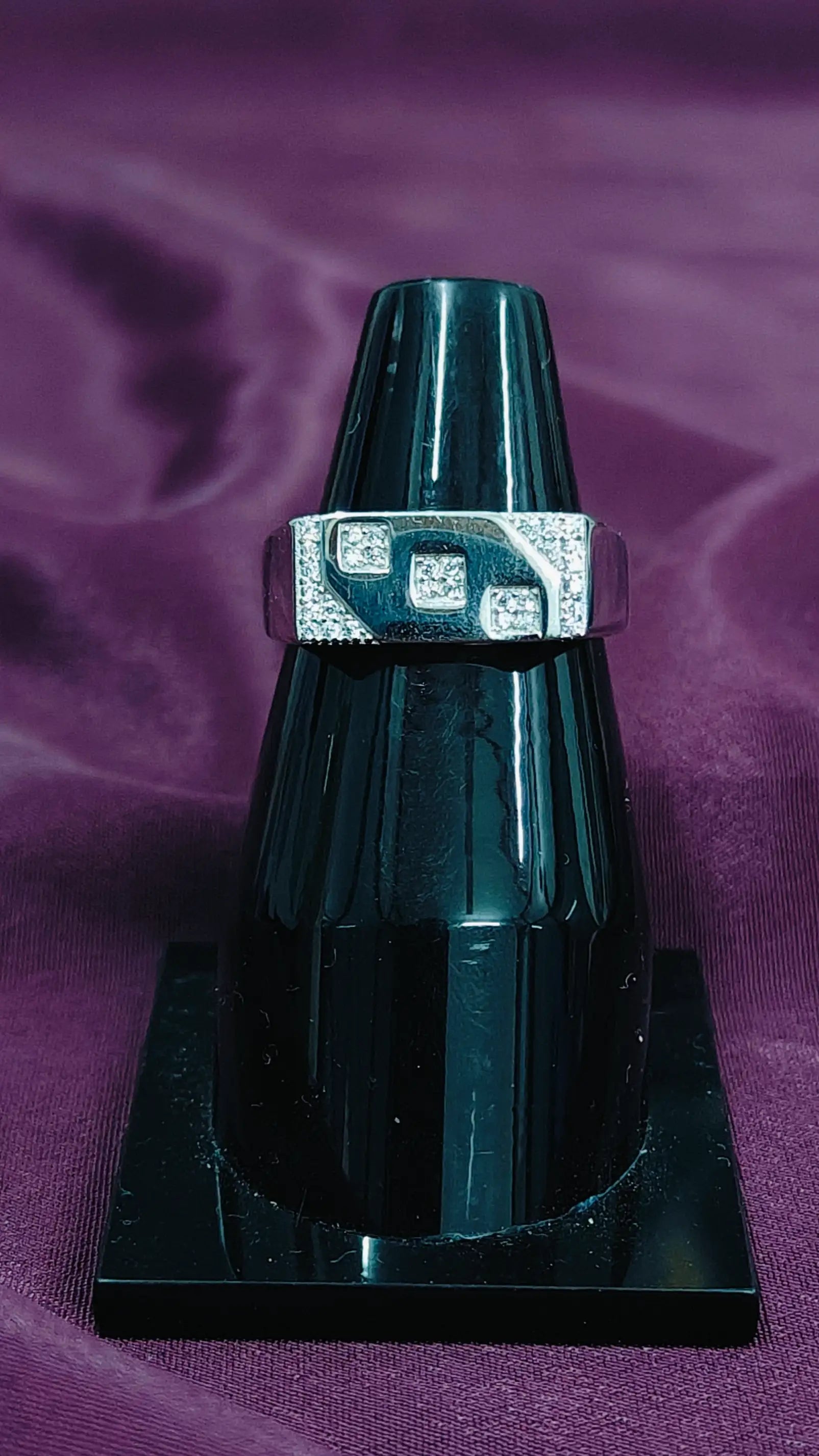 Silver ring with a green stone on a purple fabric background