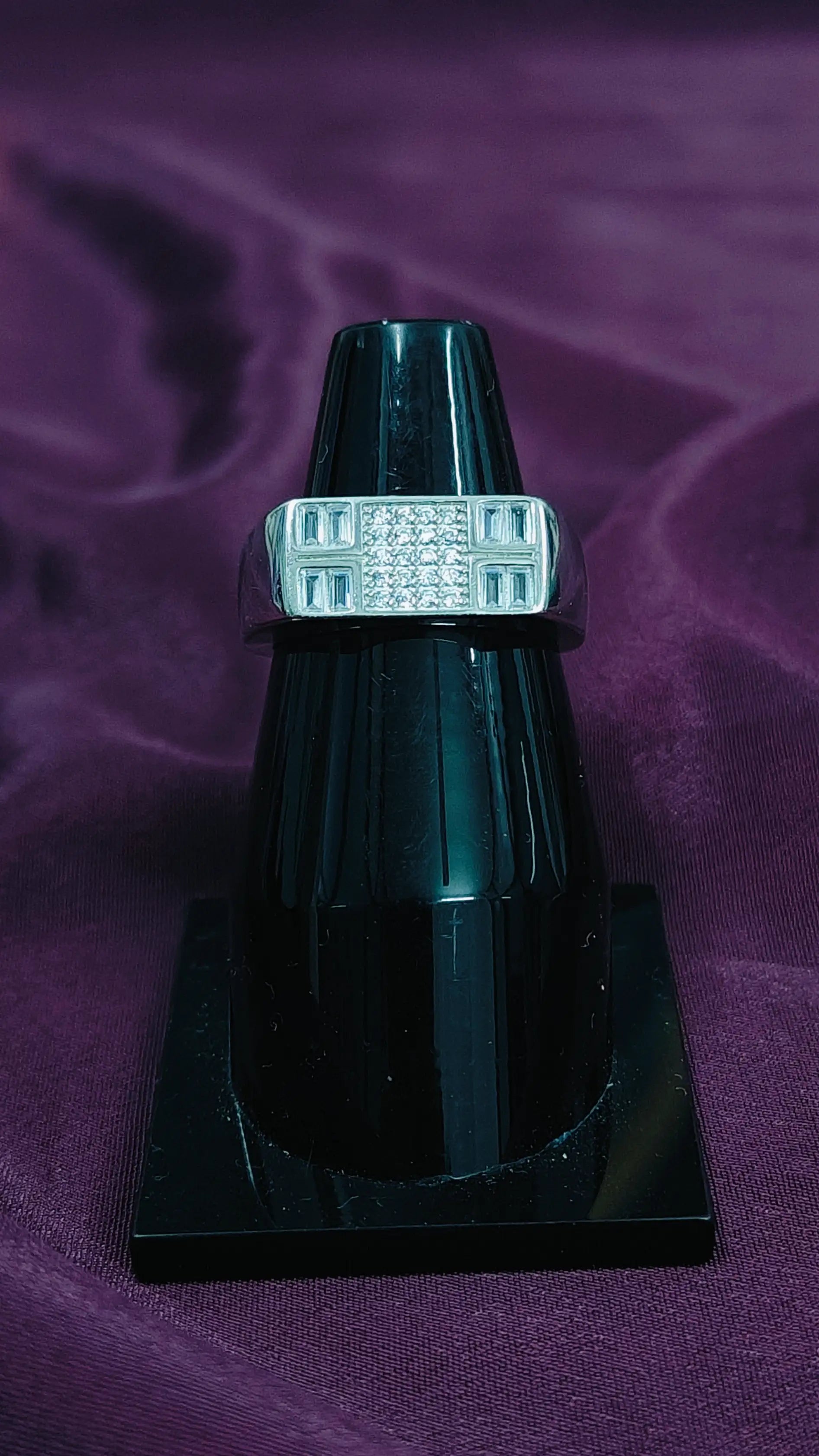 Black ring with diamond accents on a purple fabric background