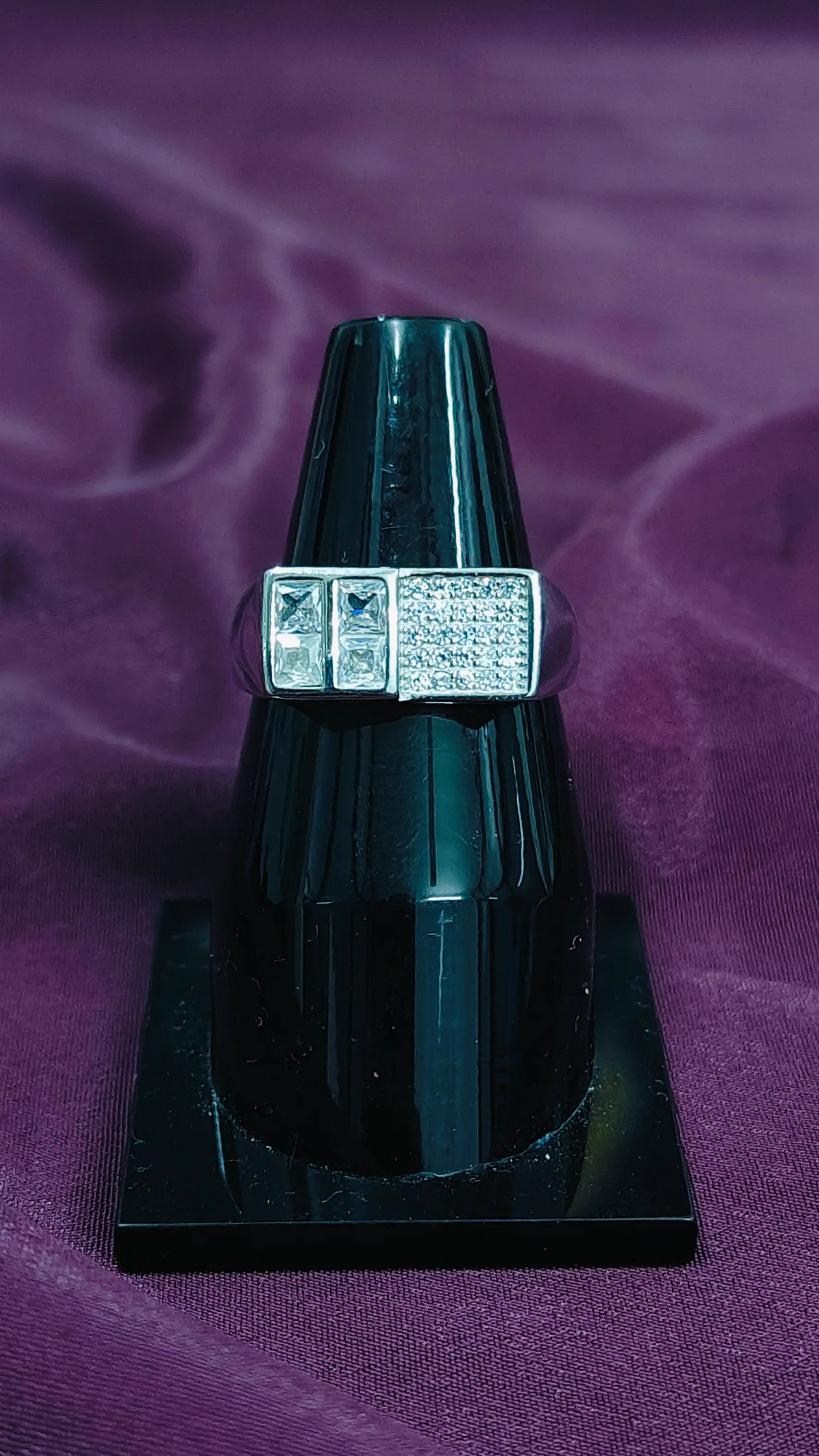 Black ring with a diamond design on a purple fabric background