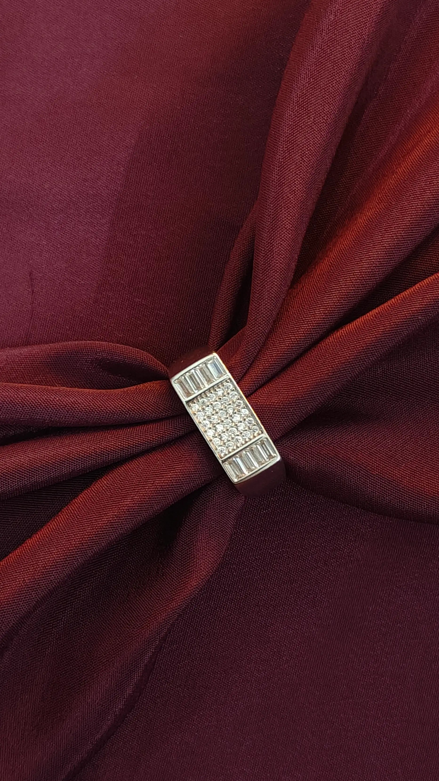 Close-up of a brooch on a burgundy fabric background