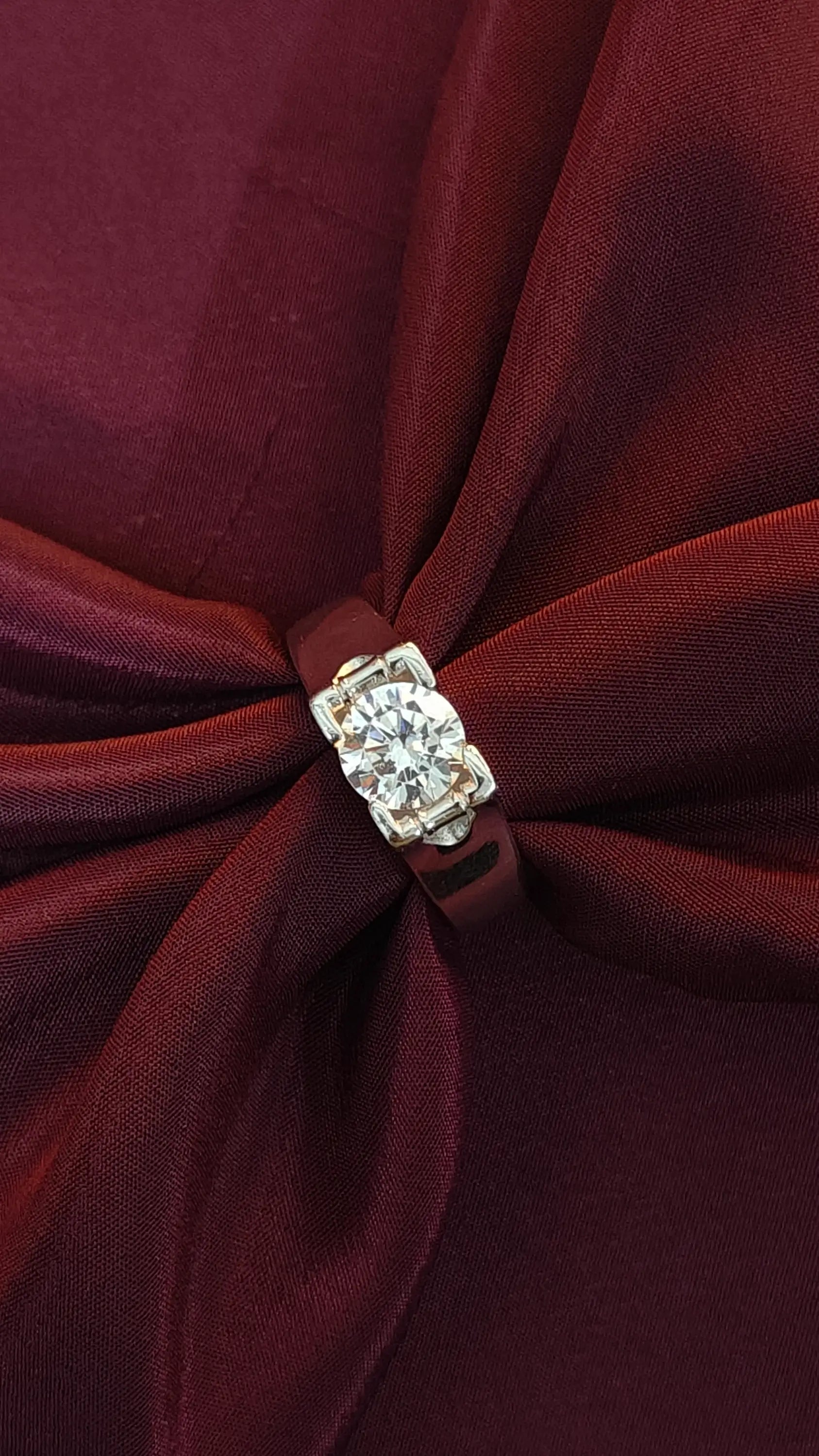 Close-up of a burgundy fabric bow with a diamond brooch in the center.