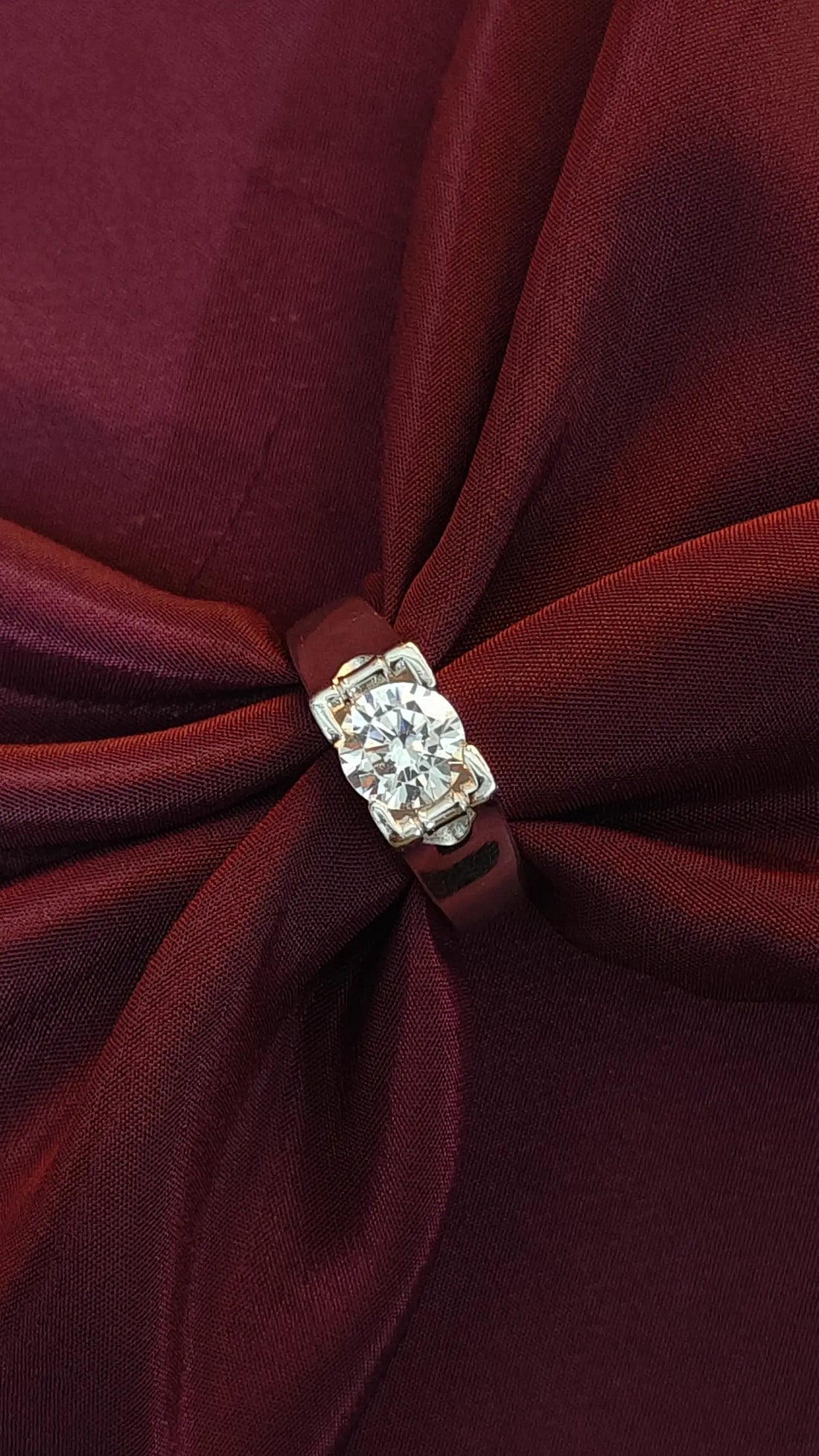 Close-up of a burgundy fabric bow with a diamond brooch in the center.