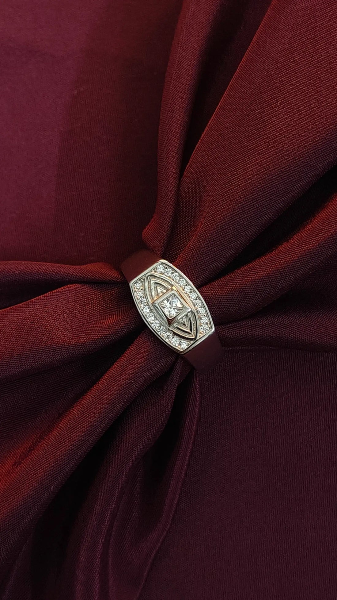 Close-up of a burgundy fabric with a decorative brooch featuring a diamond.