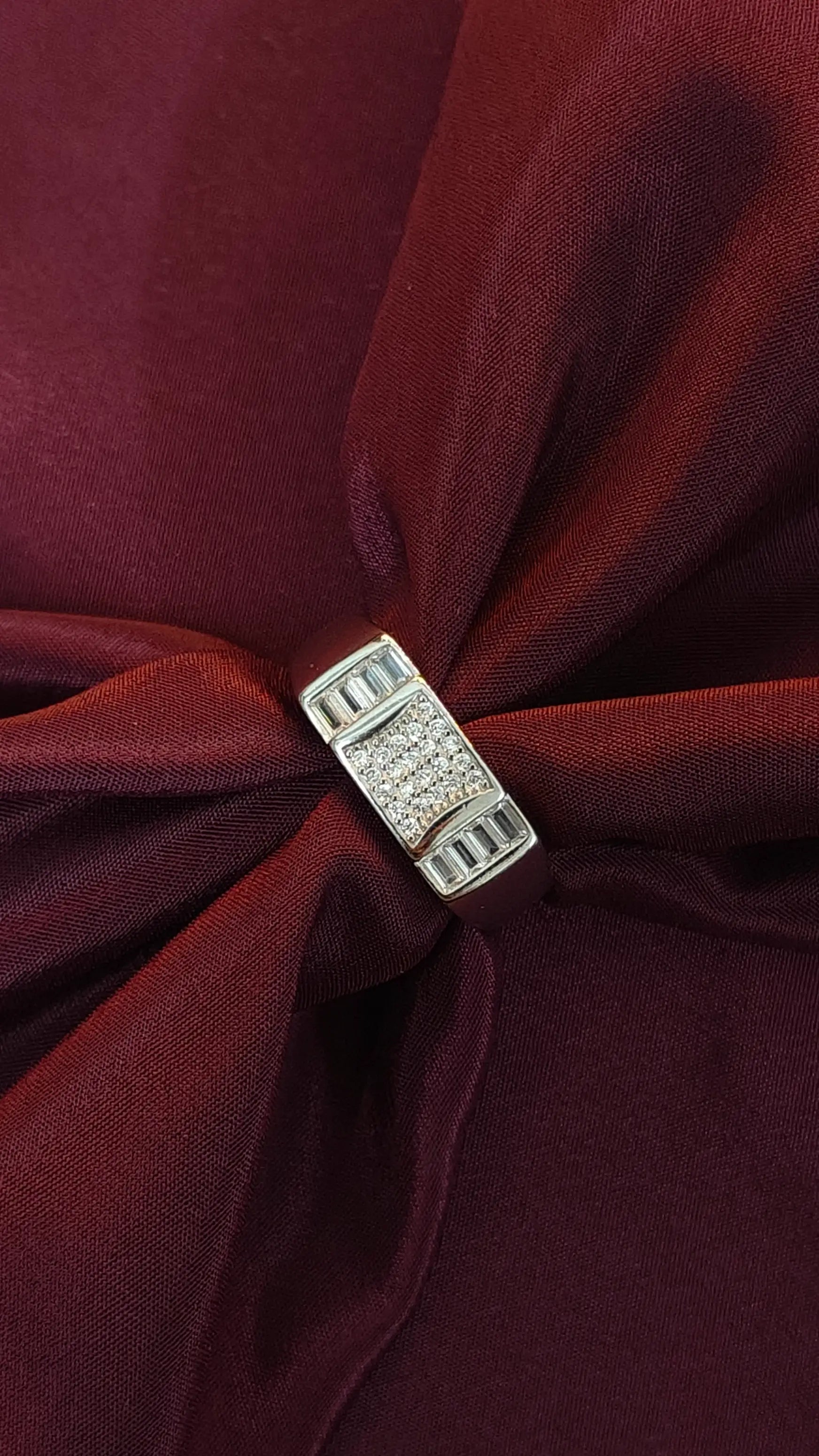 Close-up of a burgundy fabric with a decorative silver clasp.
