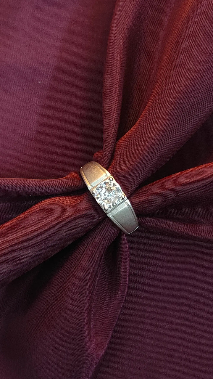 Close-up of a silver ring with gemstones on a burgundy fabric background