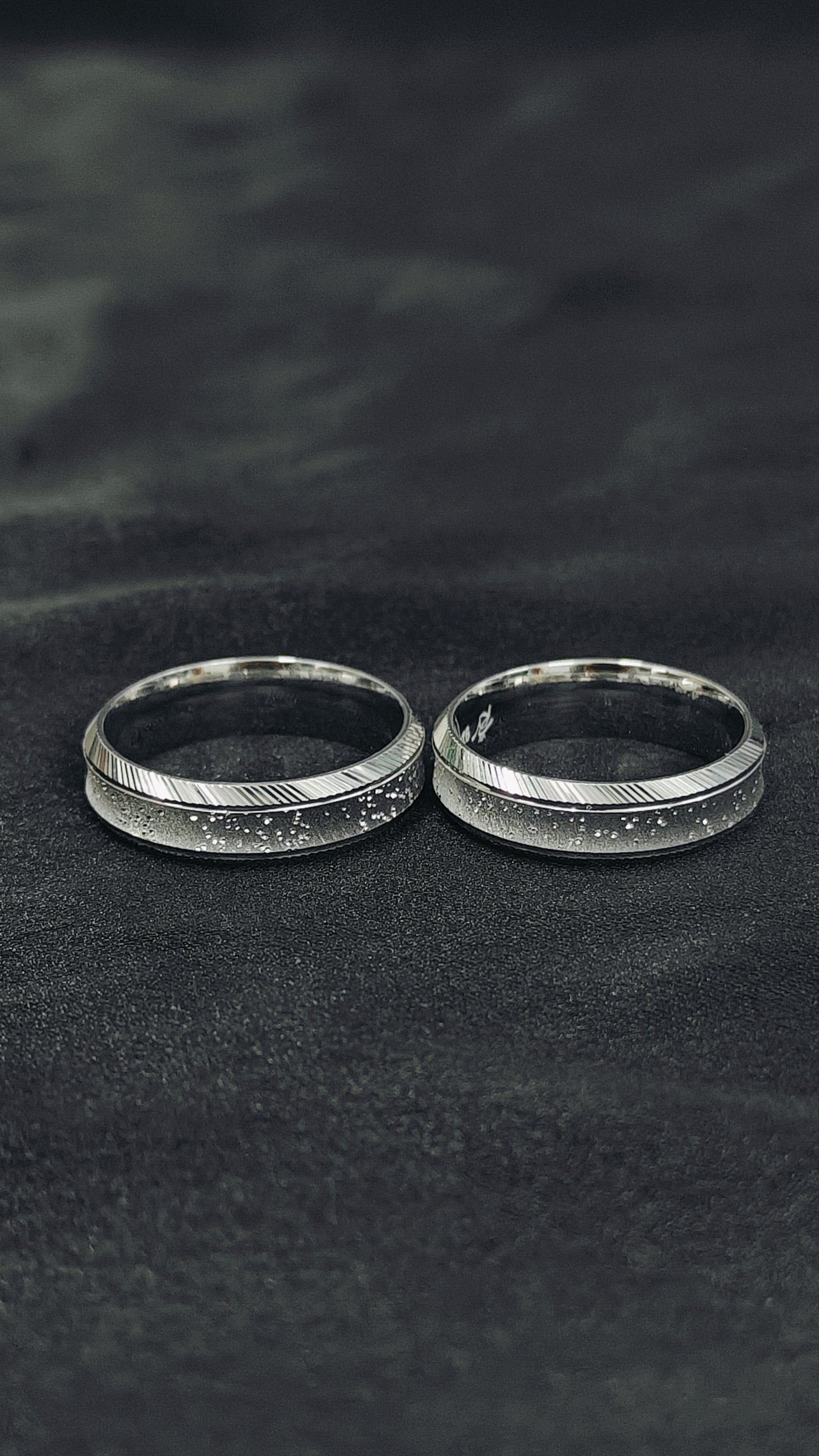 Two silver rings on a textured black surface