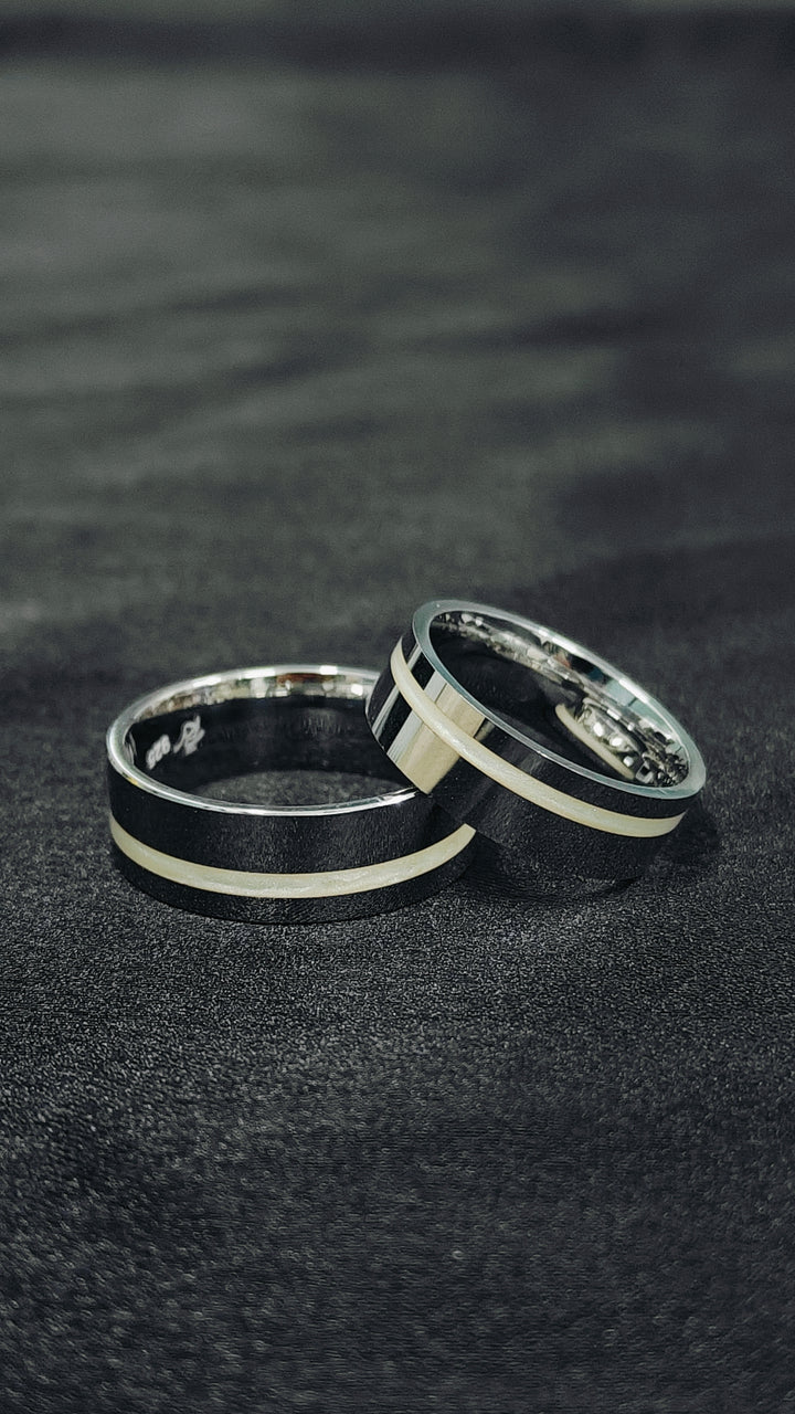 Two black and silver rings on a dark textured surface