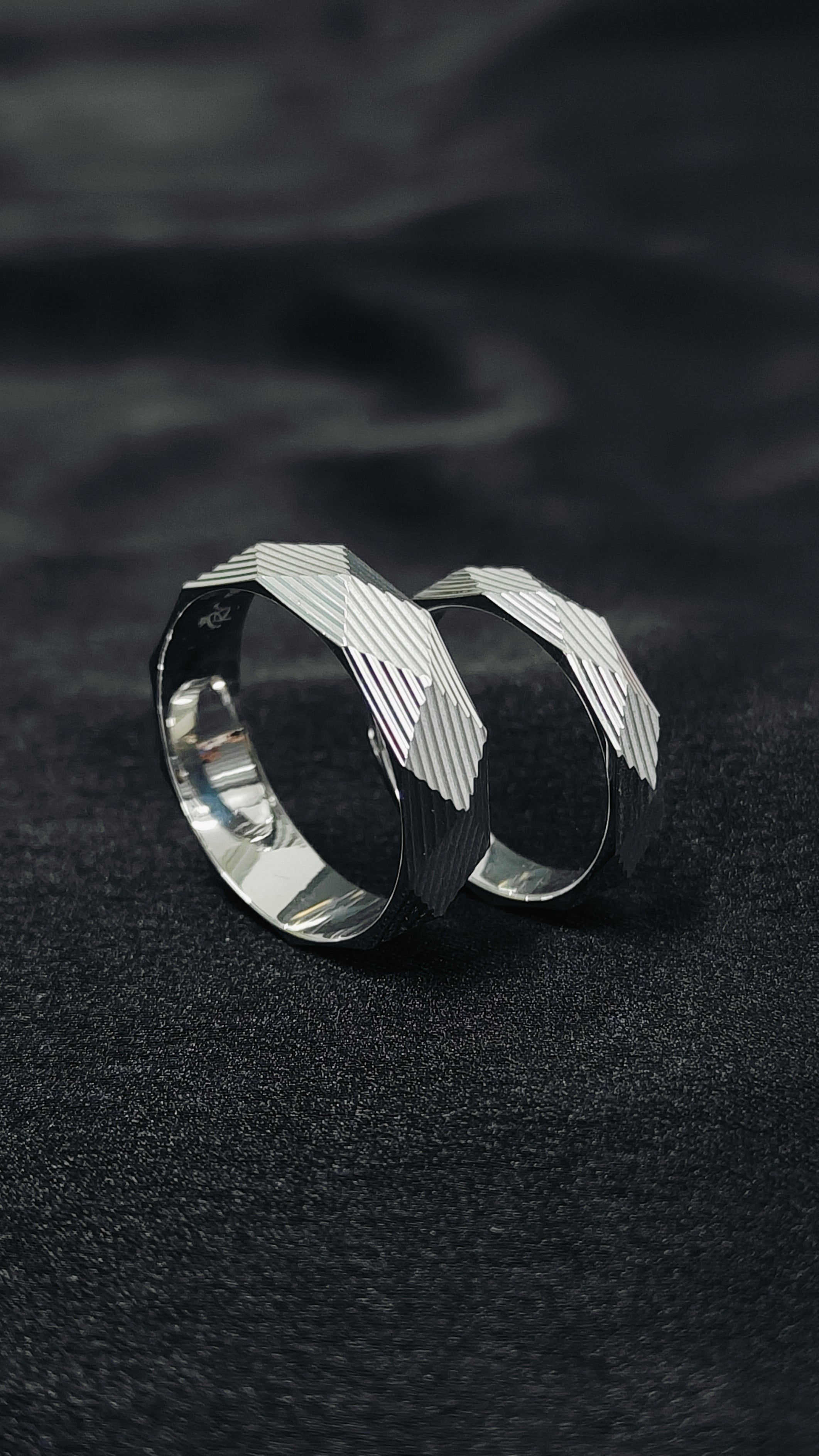 Two silver hoop earrings on a dark textured surface