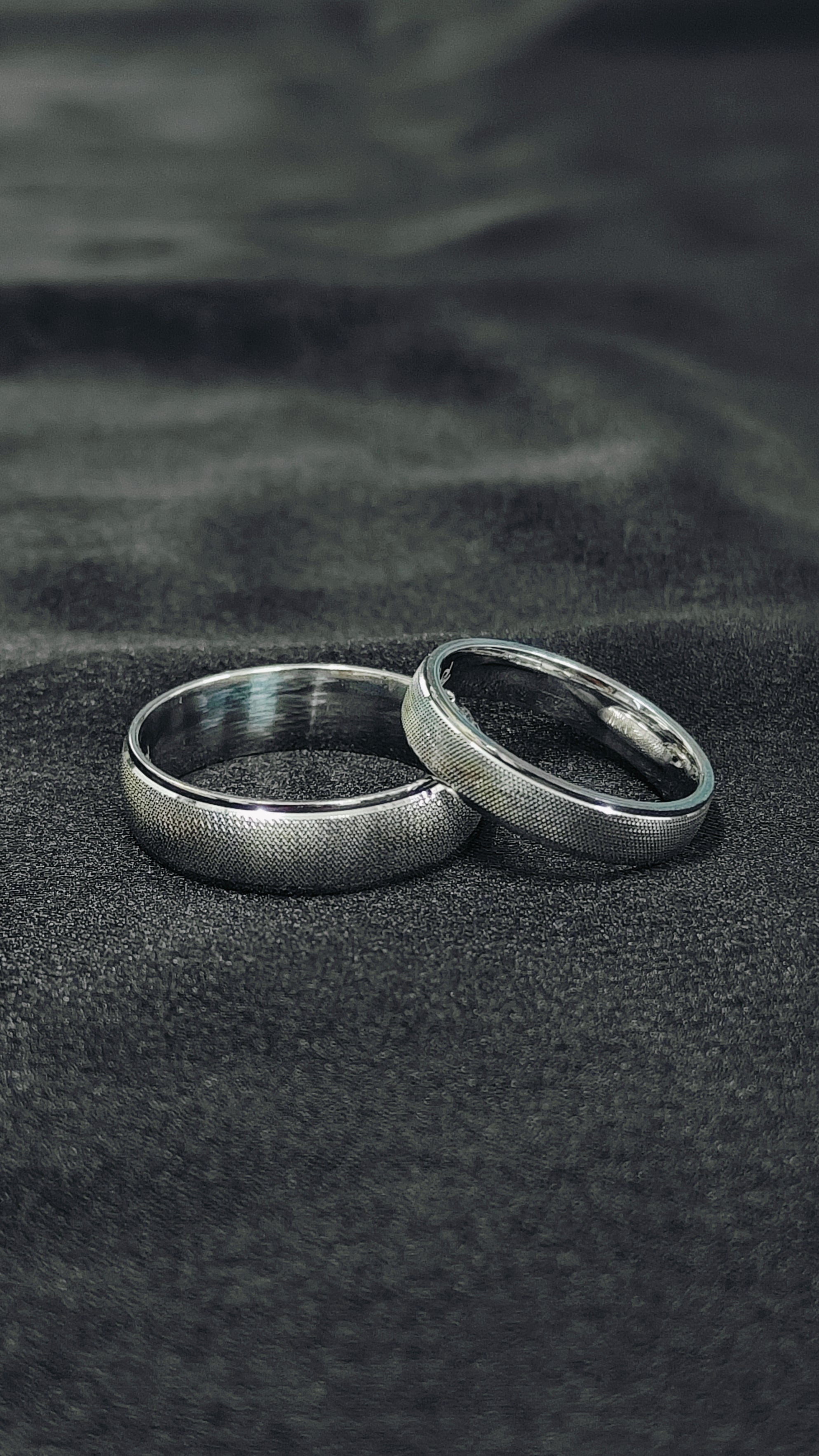 Two silver rings on a textured black surface