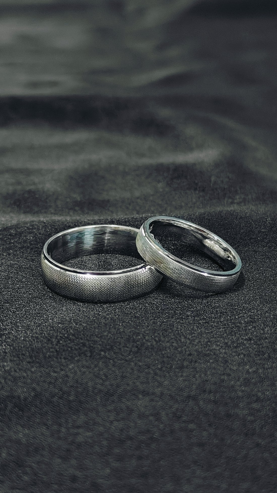 Two silver rings on a textured black surface