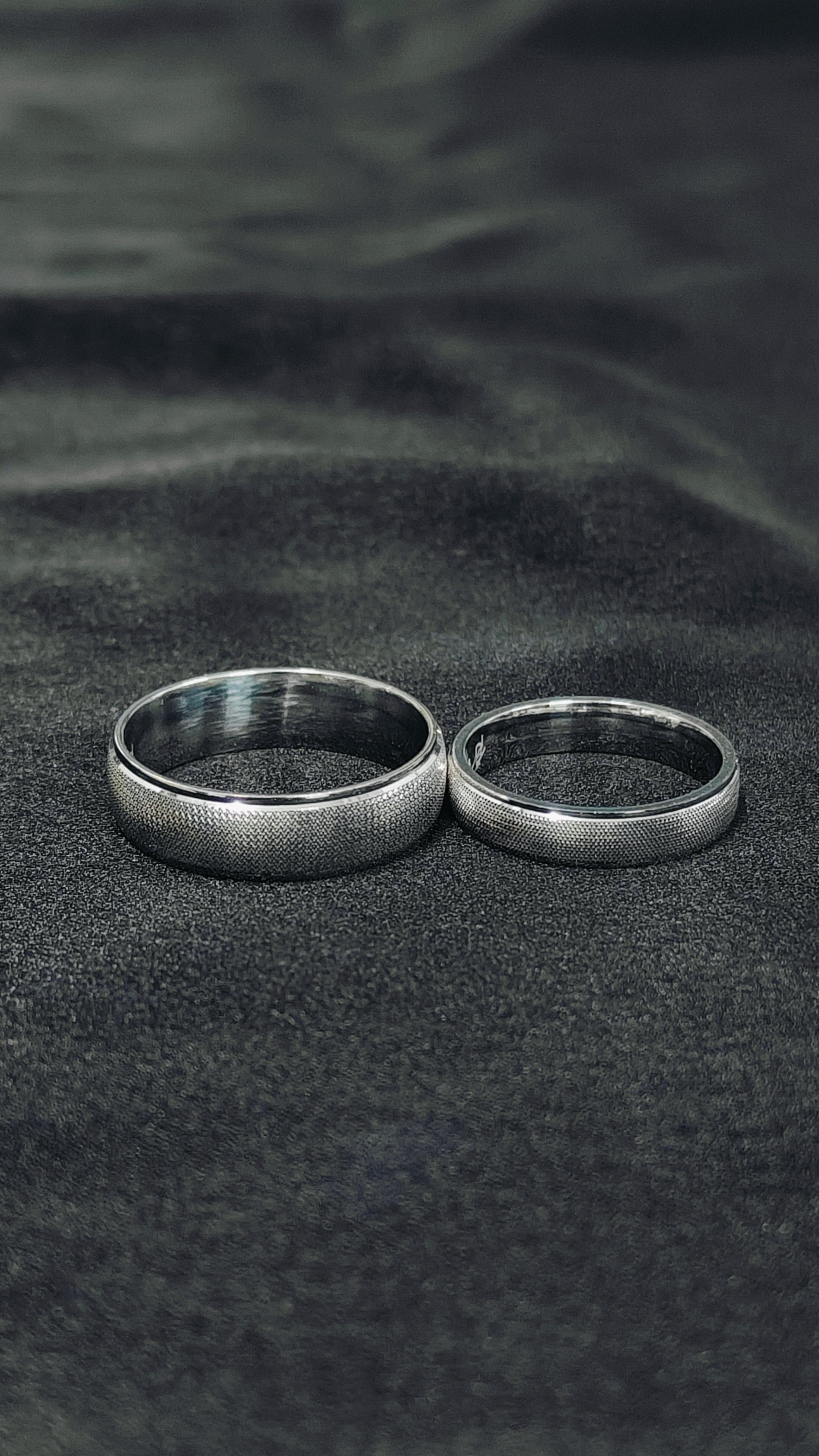 Two silver rings on a textured black surface