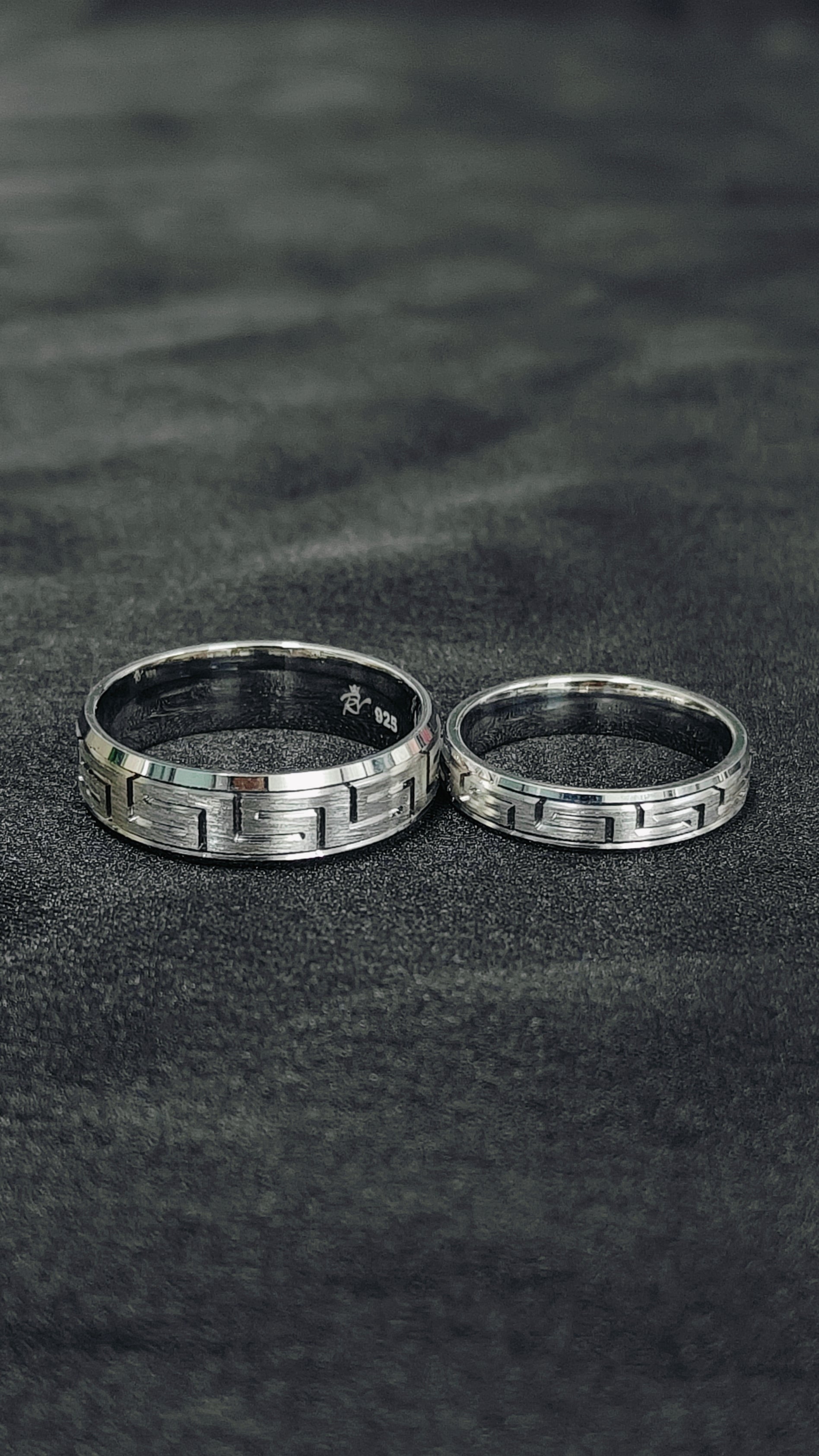 Two silver rings on a dark textured surface