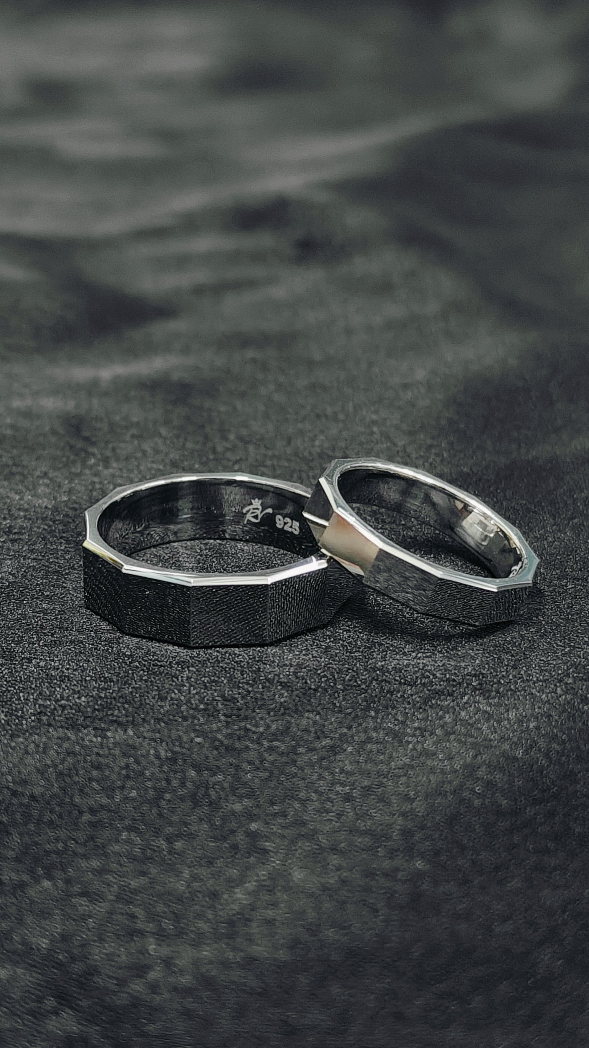 Two silver rings on a textured black surface