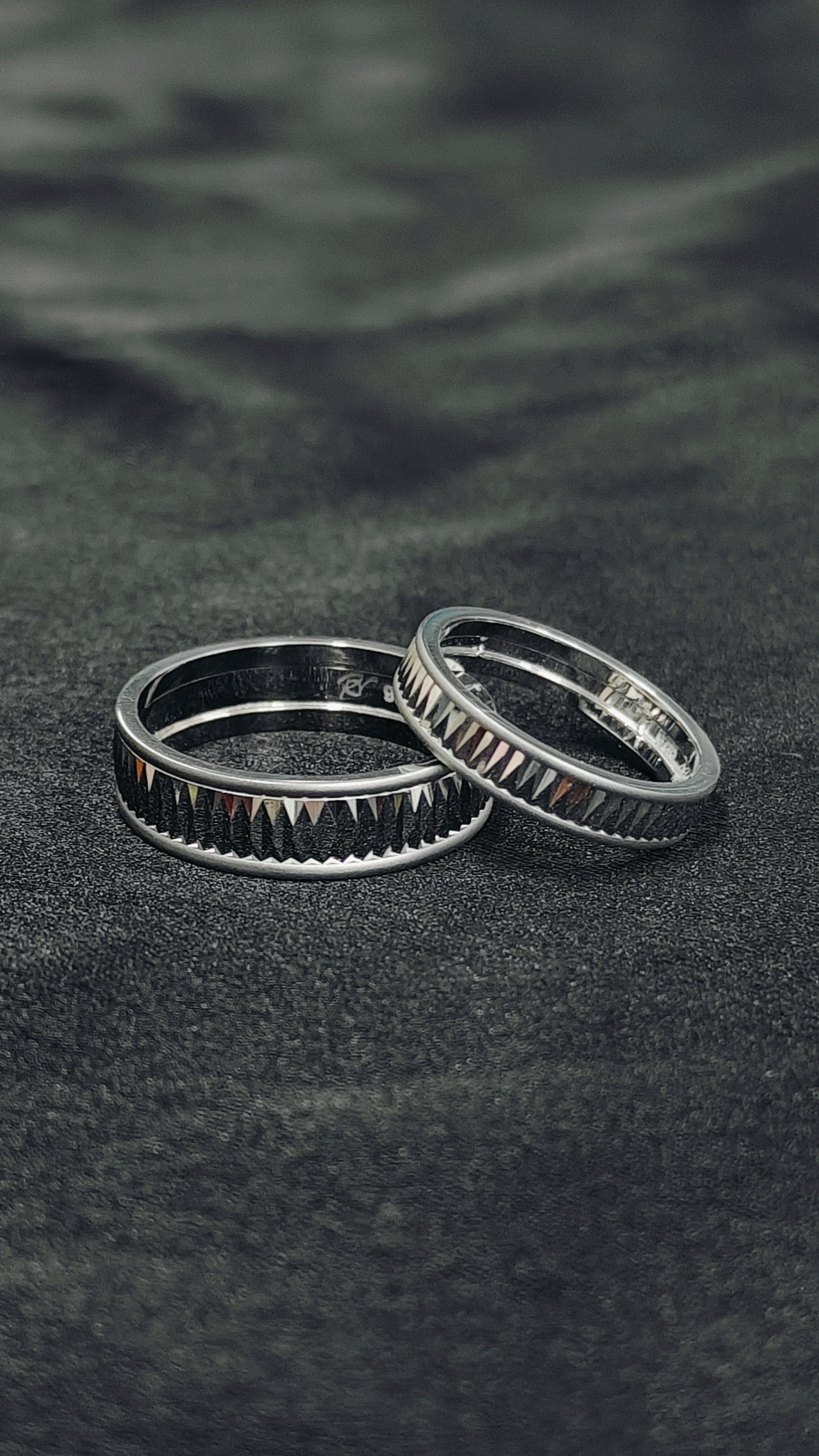 Two silver rings on a textured black surface