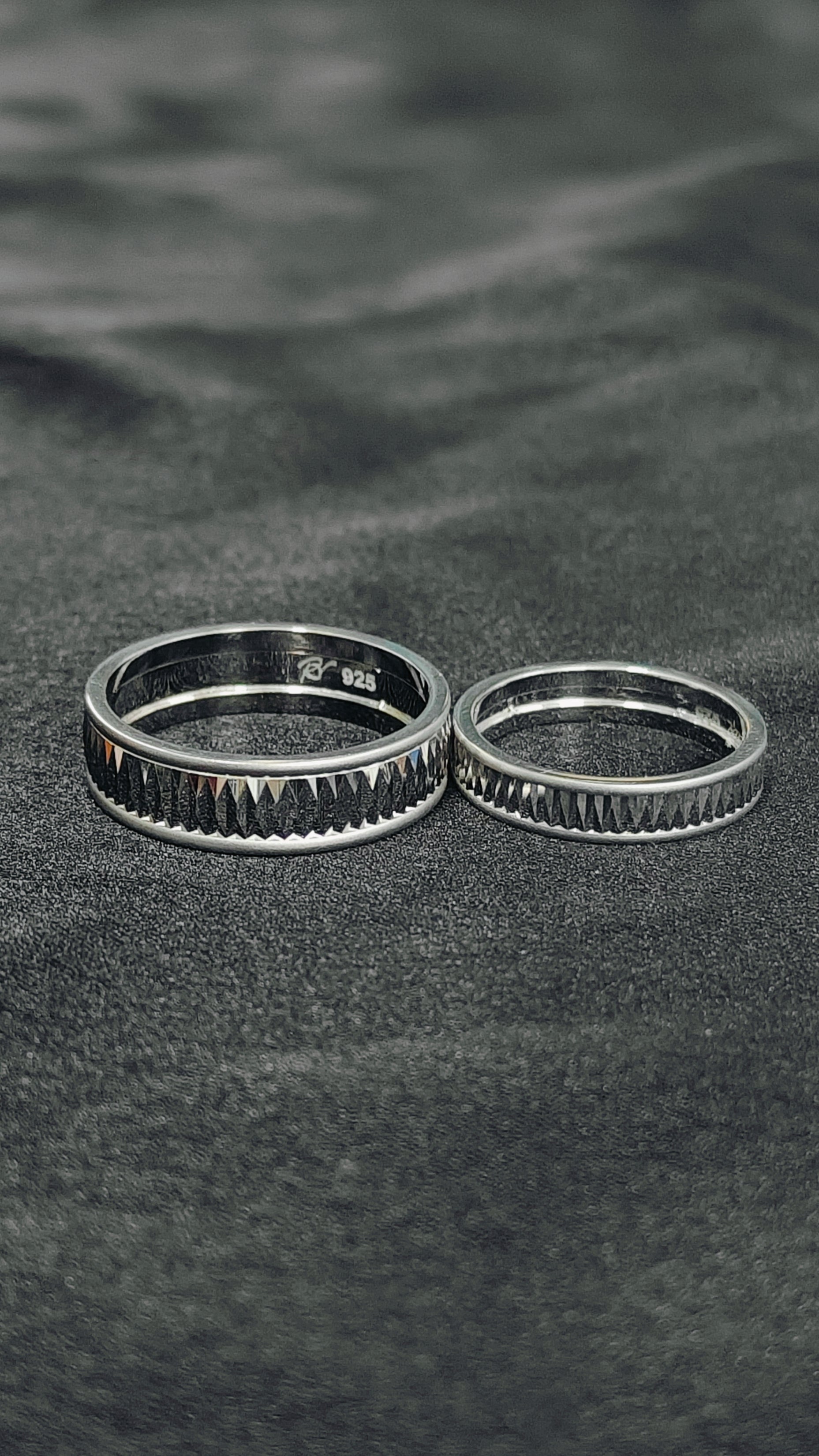 Two silver rings on a textured black surface