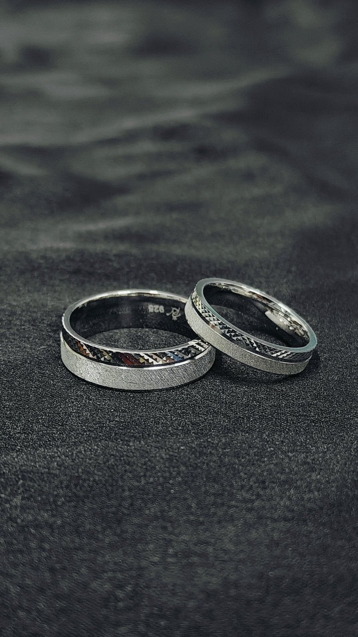 Two silver rings on a dark textured surface