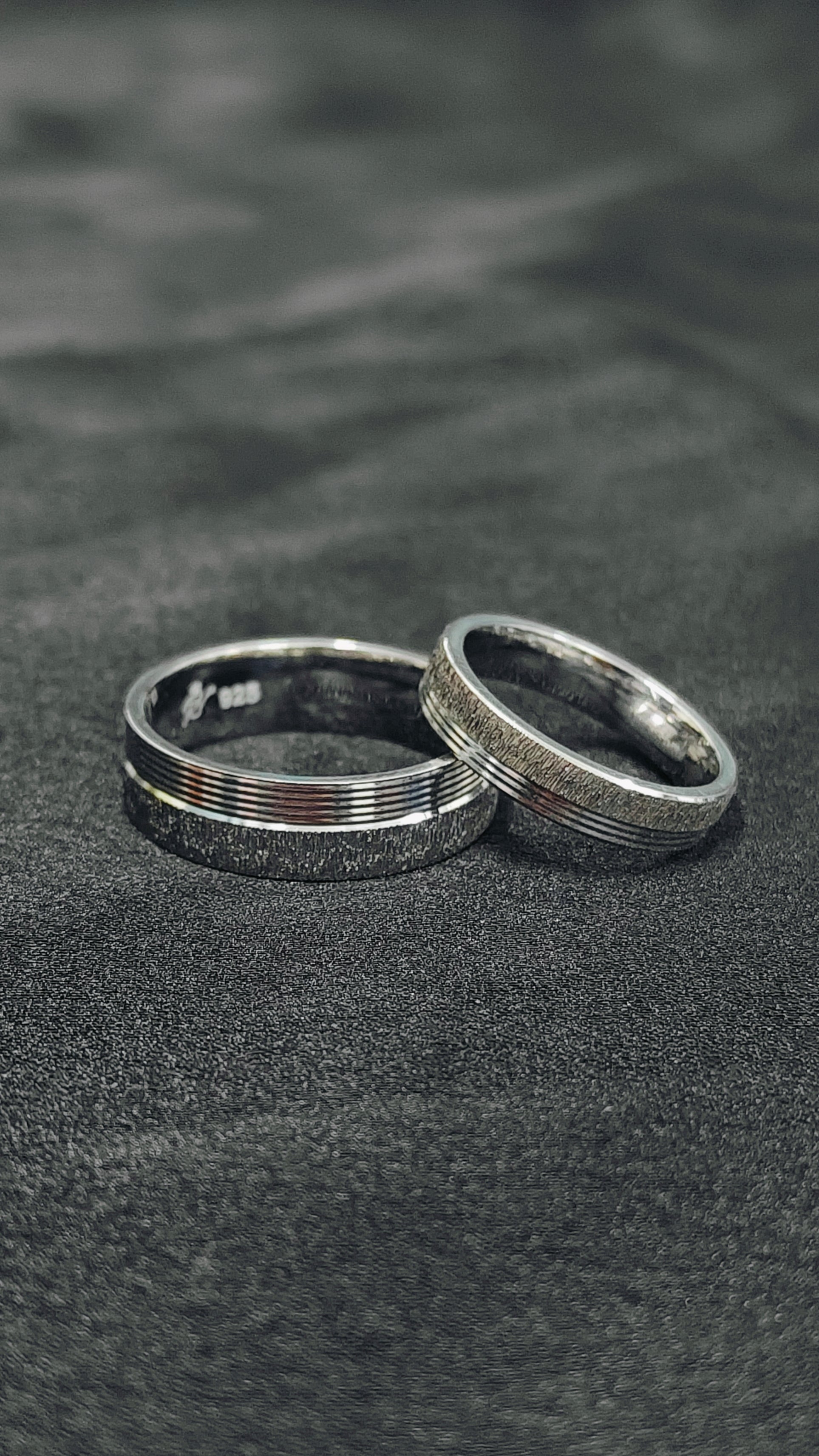 Two silver rings on a textured black surface