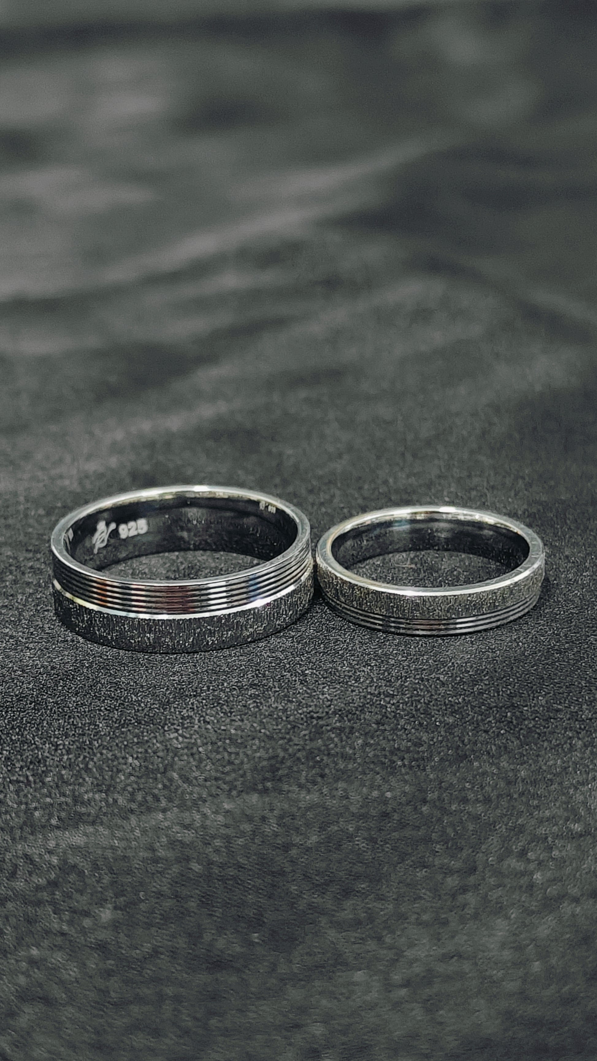 Two silver rings on a textured black surface