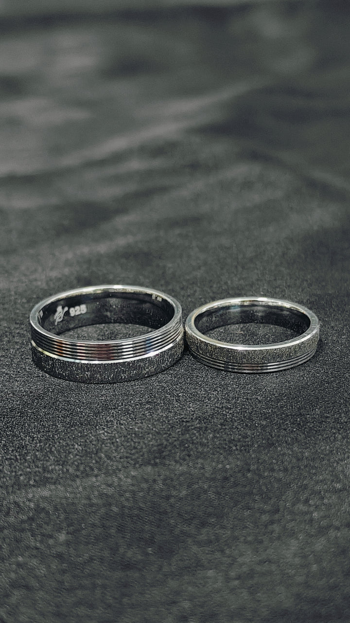 Two silver rings on a textured black surface