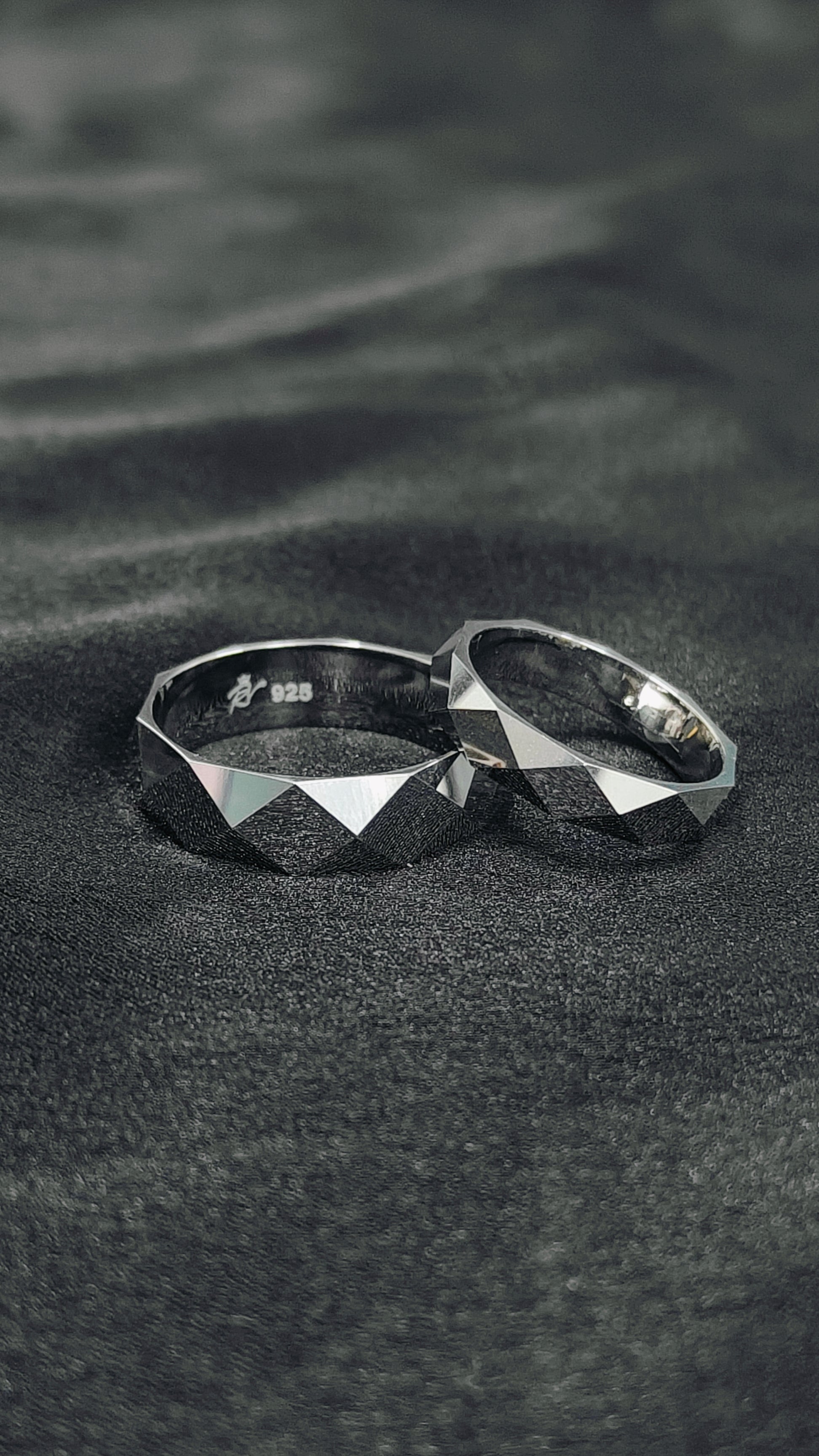 Two silver rings on a textured black surface
