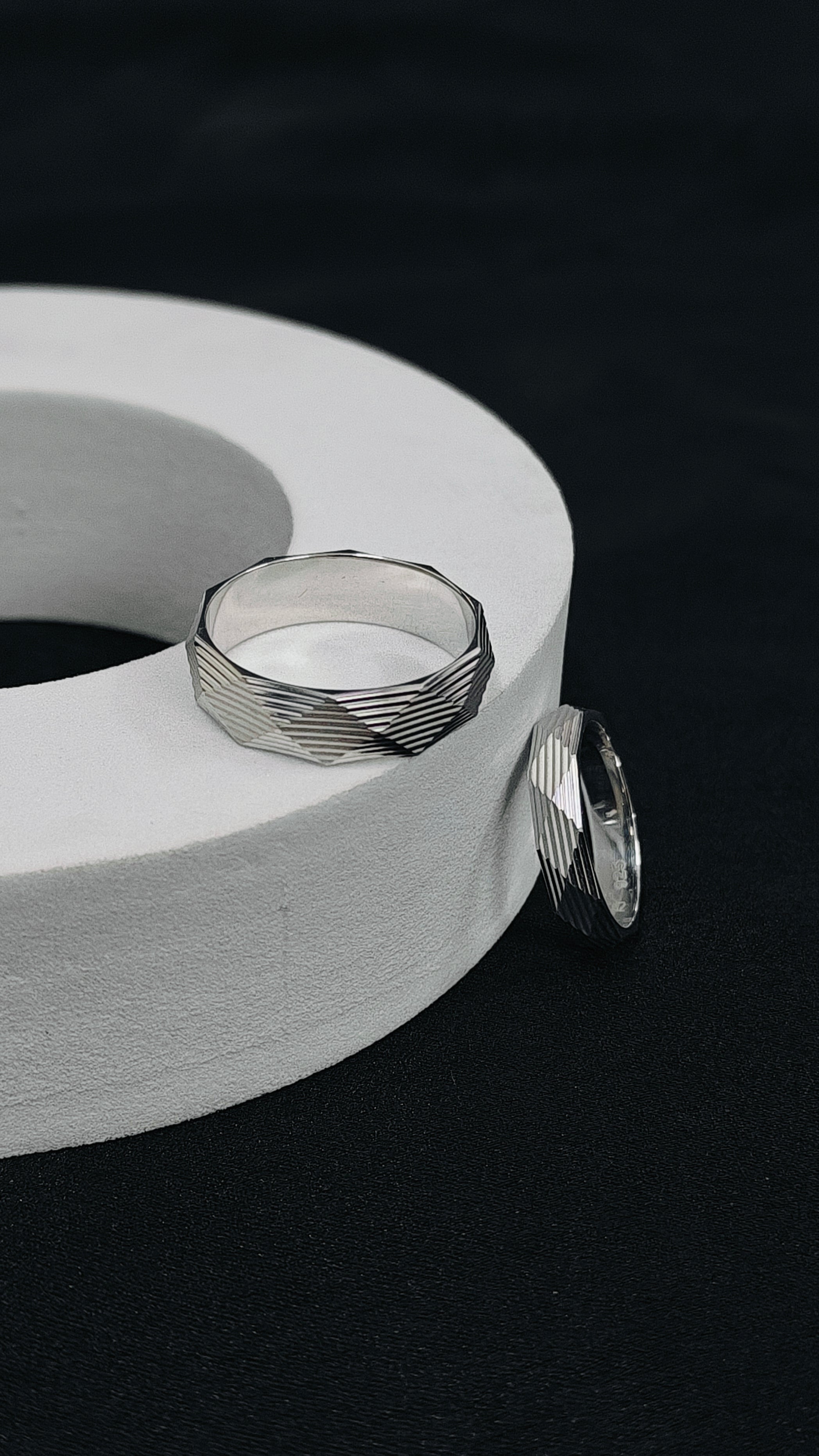 Two silver rings on a white cylindrical object against a black background