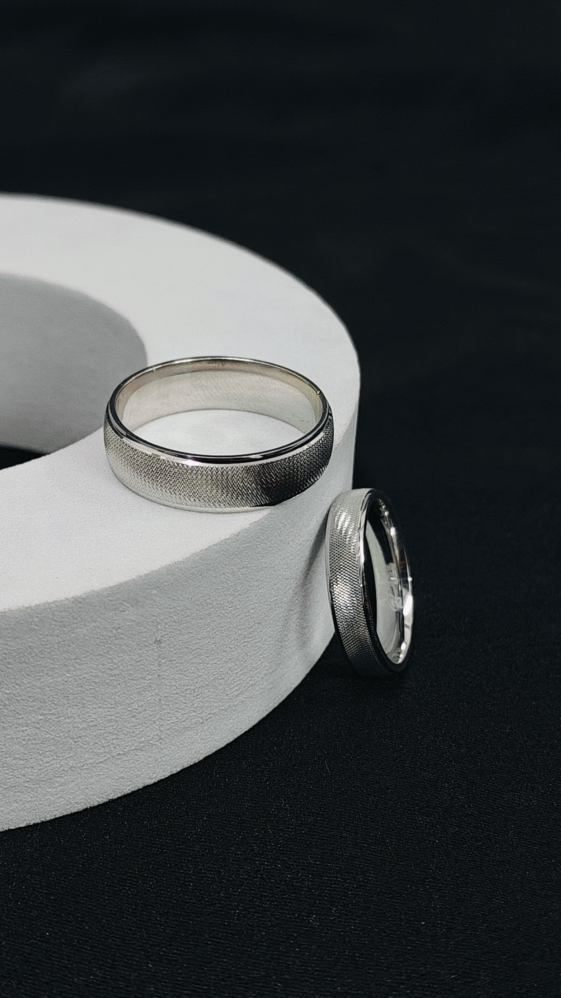 Two silver rings on a white cylindrical object with a dark background