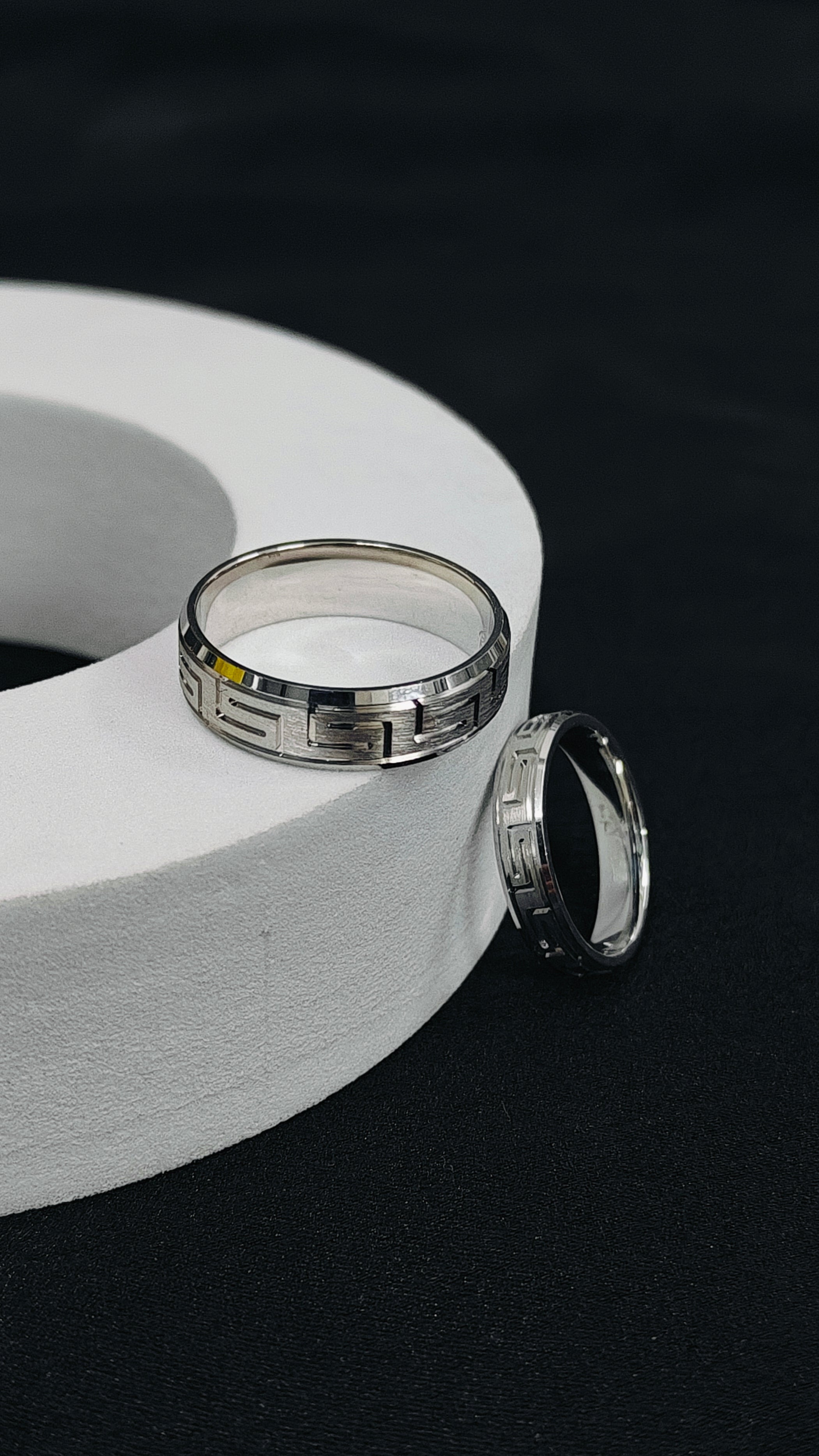 Two silver rings on a white circular object against a black background