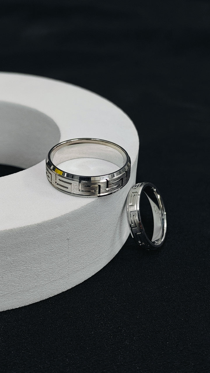 Two silver rings on a white circular object against a black background