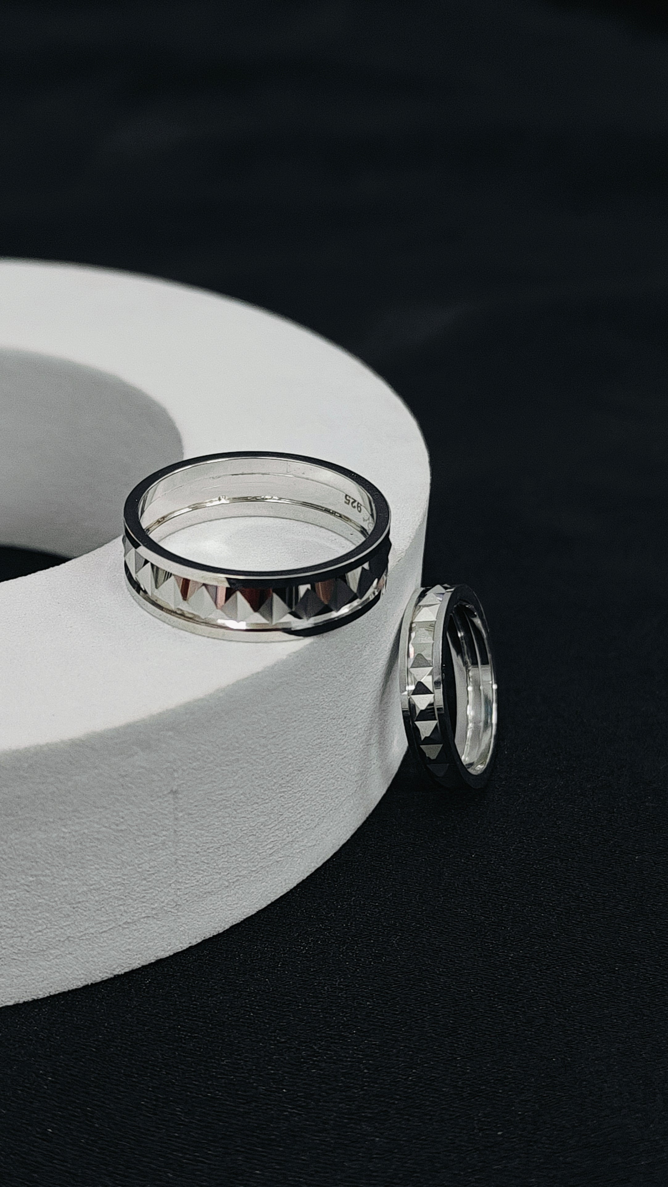 Two silver rings on a white cylindrical object against a black background