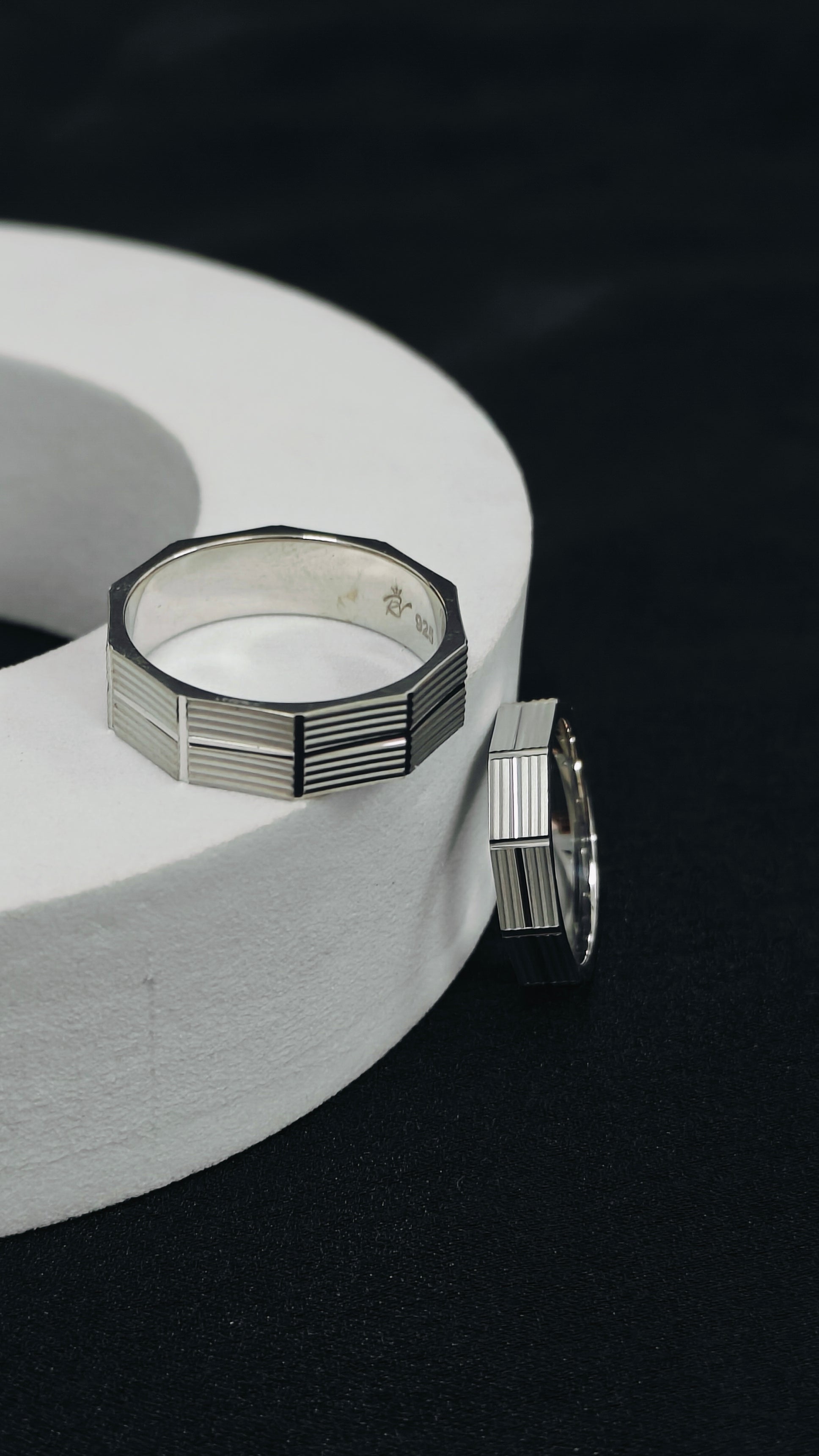 Silver rings on a white circular stand with a black background