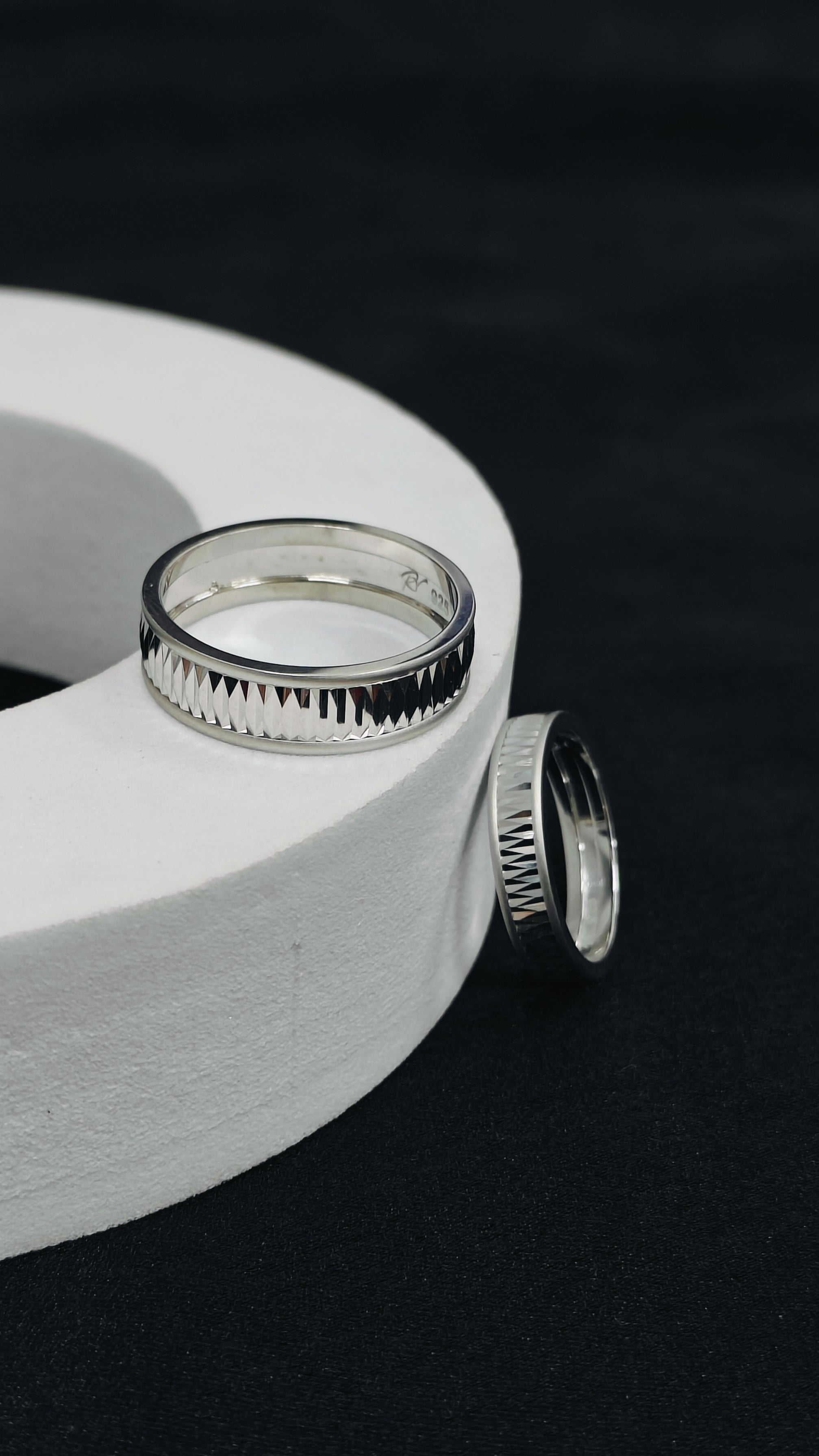 Silver rings on a white cylindrical object against a black background