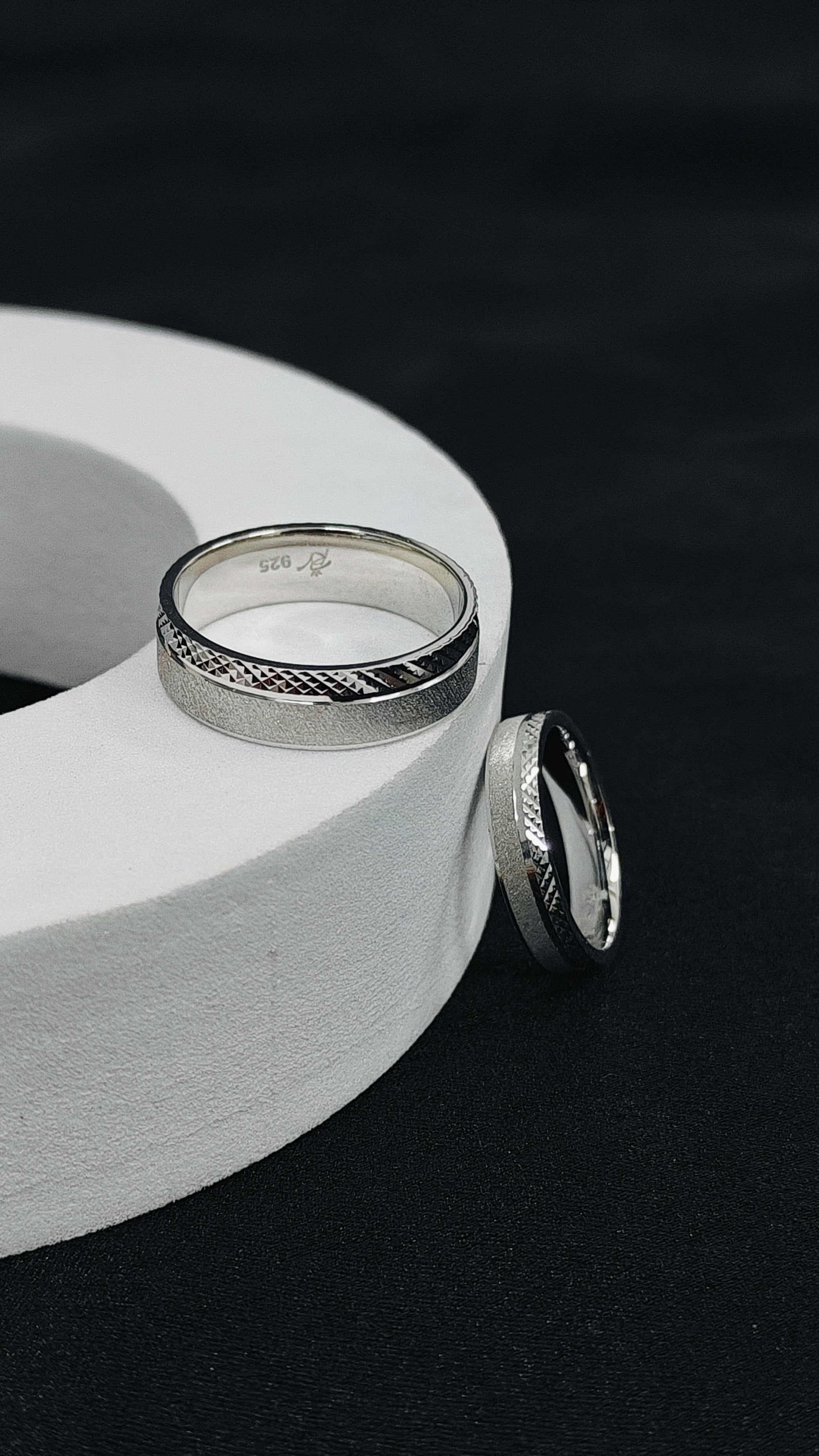 Two silver rings on a white cylindrical object against a black background