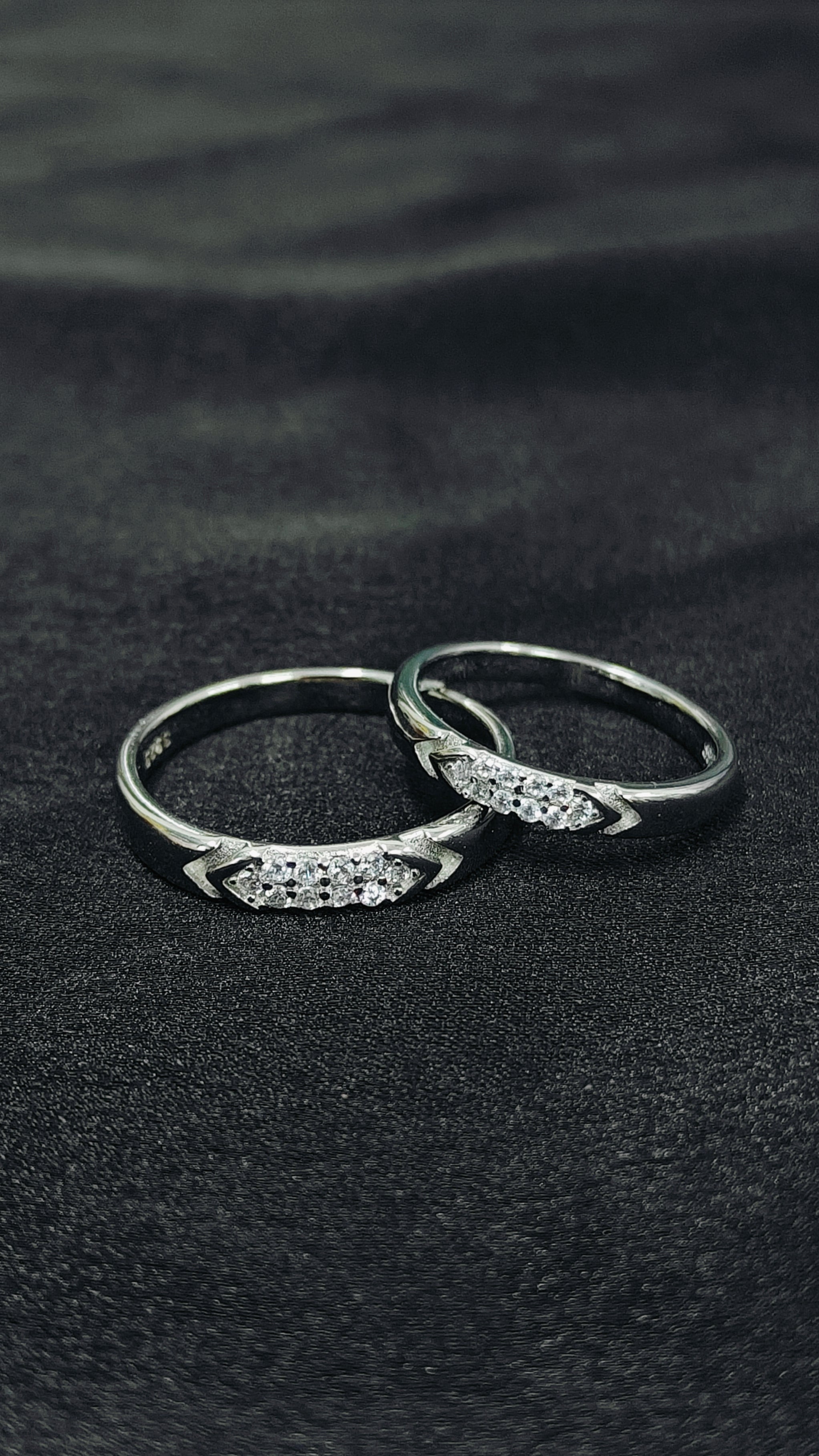 Two silver rings with gemstones on a black fabric background
