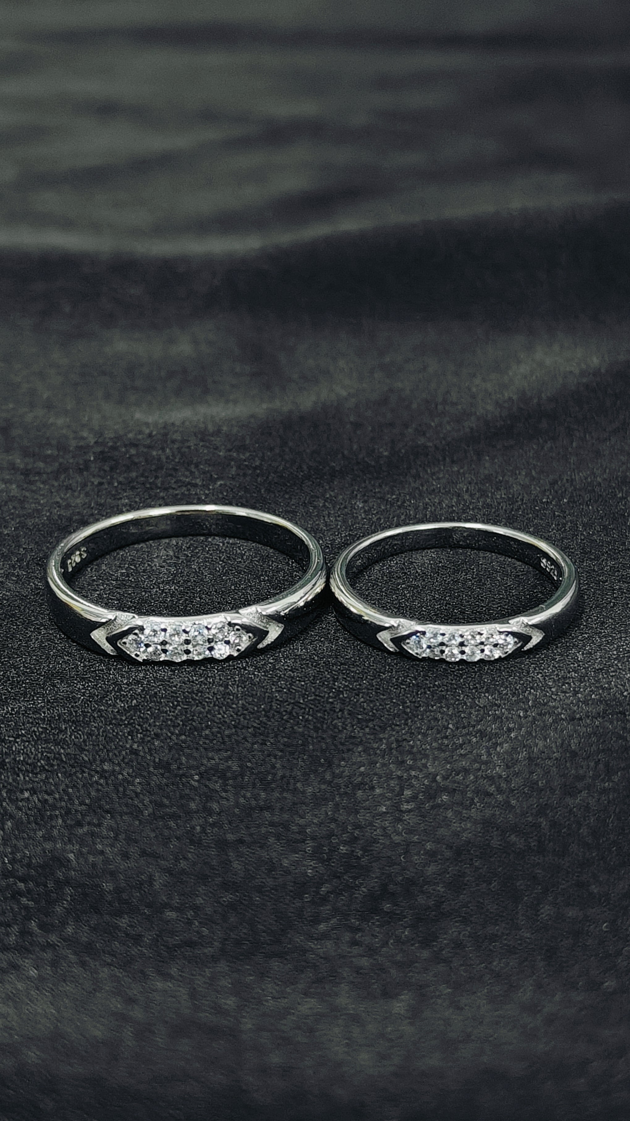 Two silver rings with gemstones on a black fabric background