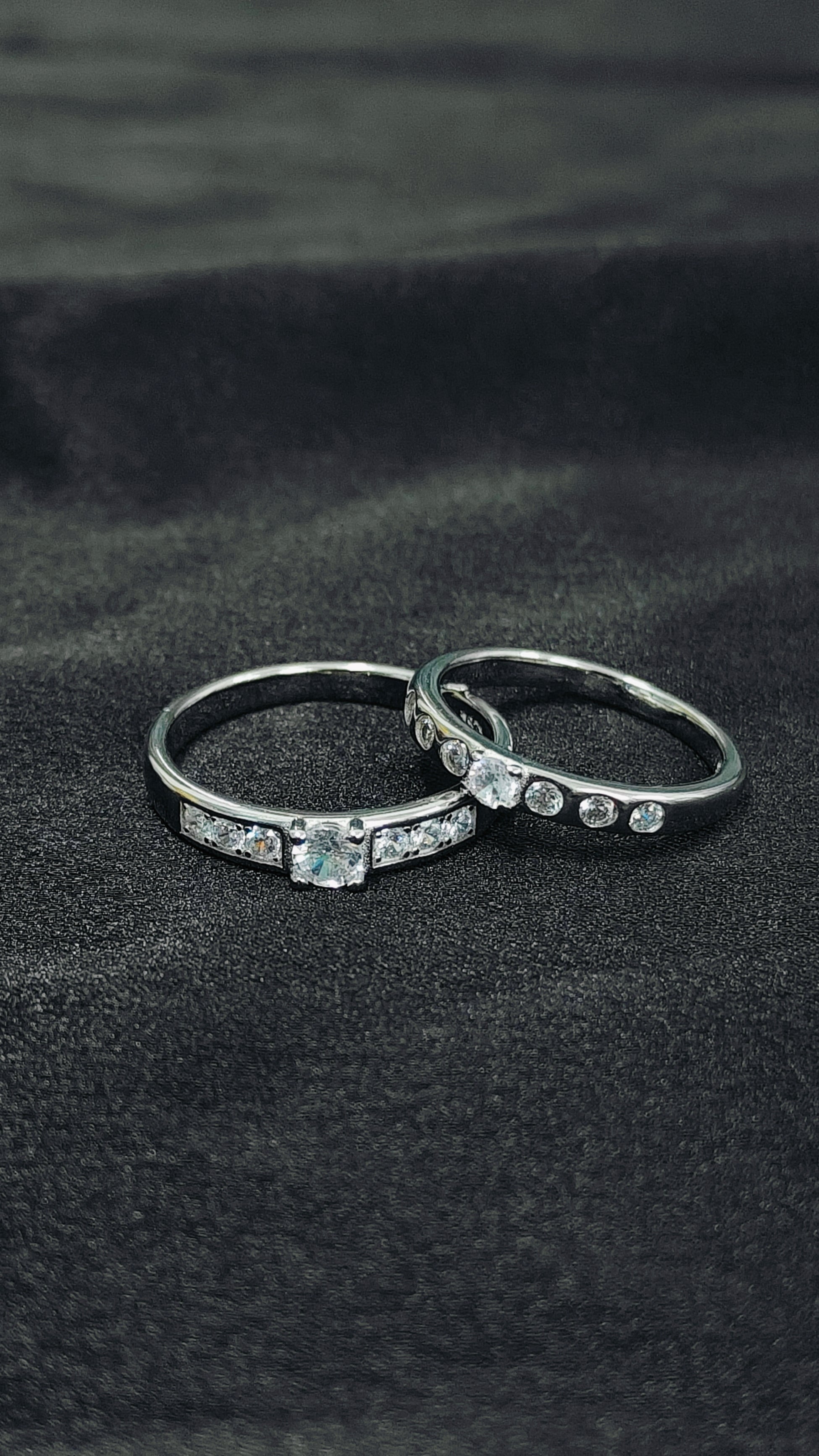Two silver rings with gemstones on a black fabric background
